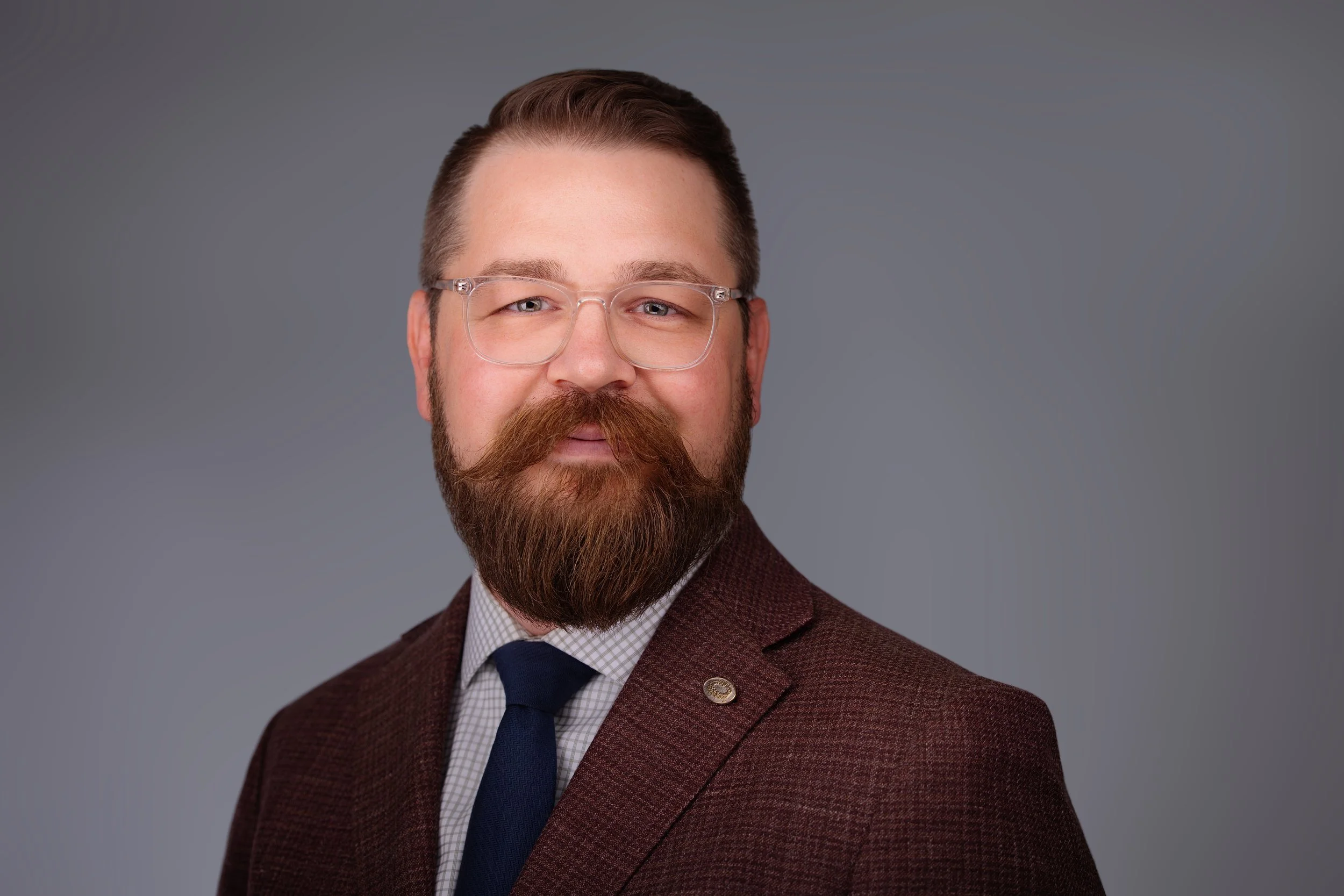 Very distinguished Kansas City man with a nice suit on with glasses with gray background