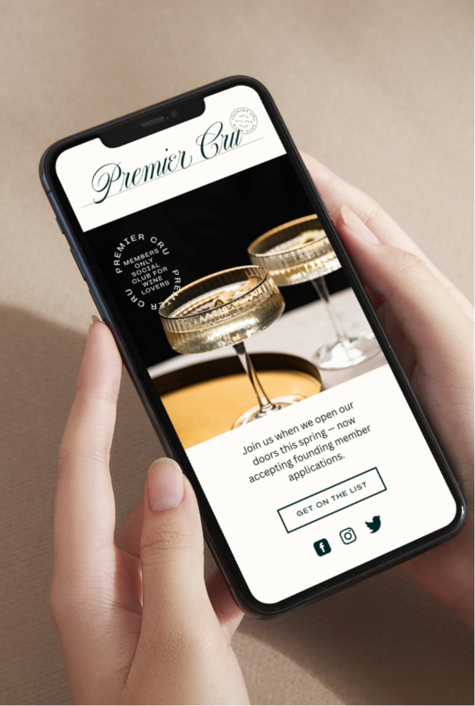 A person holding a smartphone displaying a website for Premier Cru, featuring two glasses of champagne and an invitation to join a wine club.