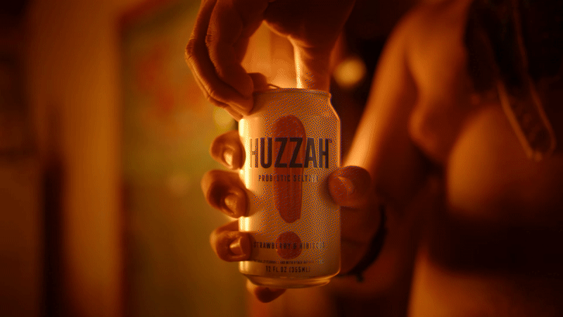 Person holding a can of HUZZAH probiotic seltzer.