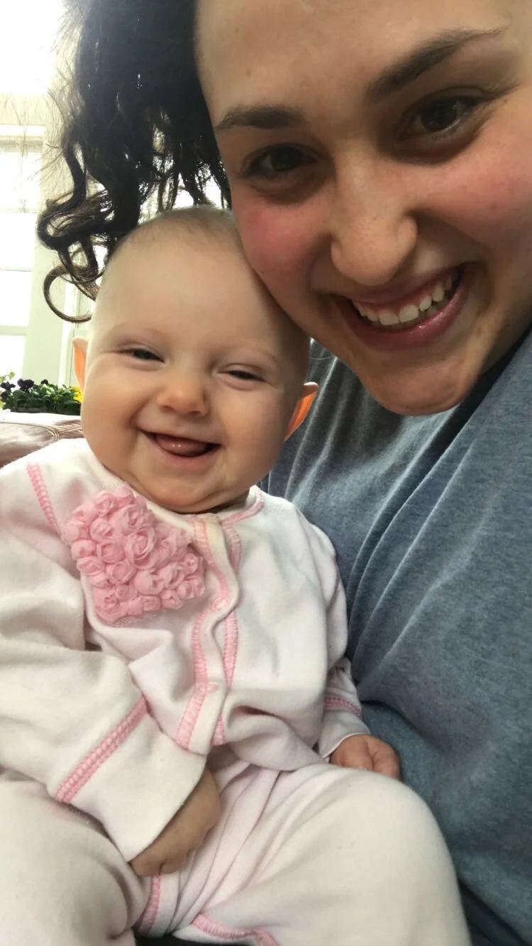 A smiling woman and a happy baby sitting close together.