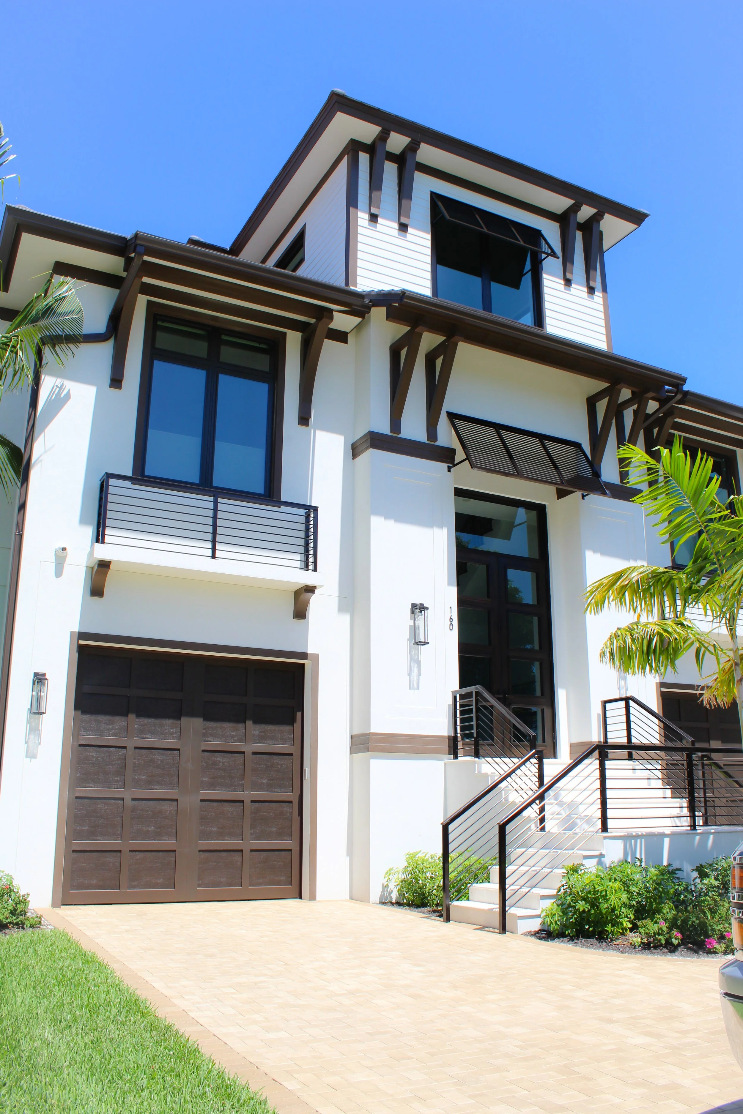 Modern three-story house with white exterior, large windows, and a large front door.