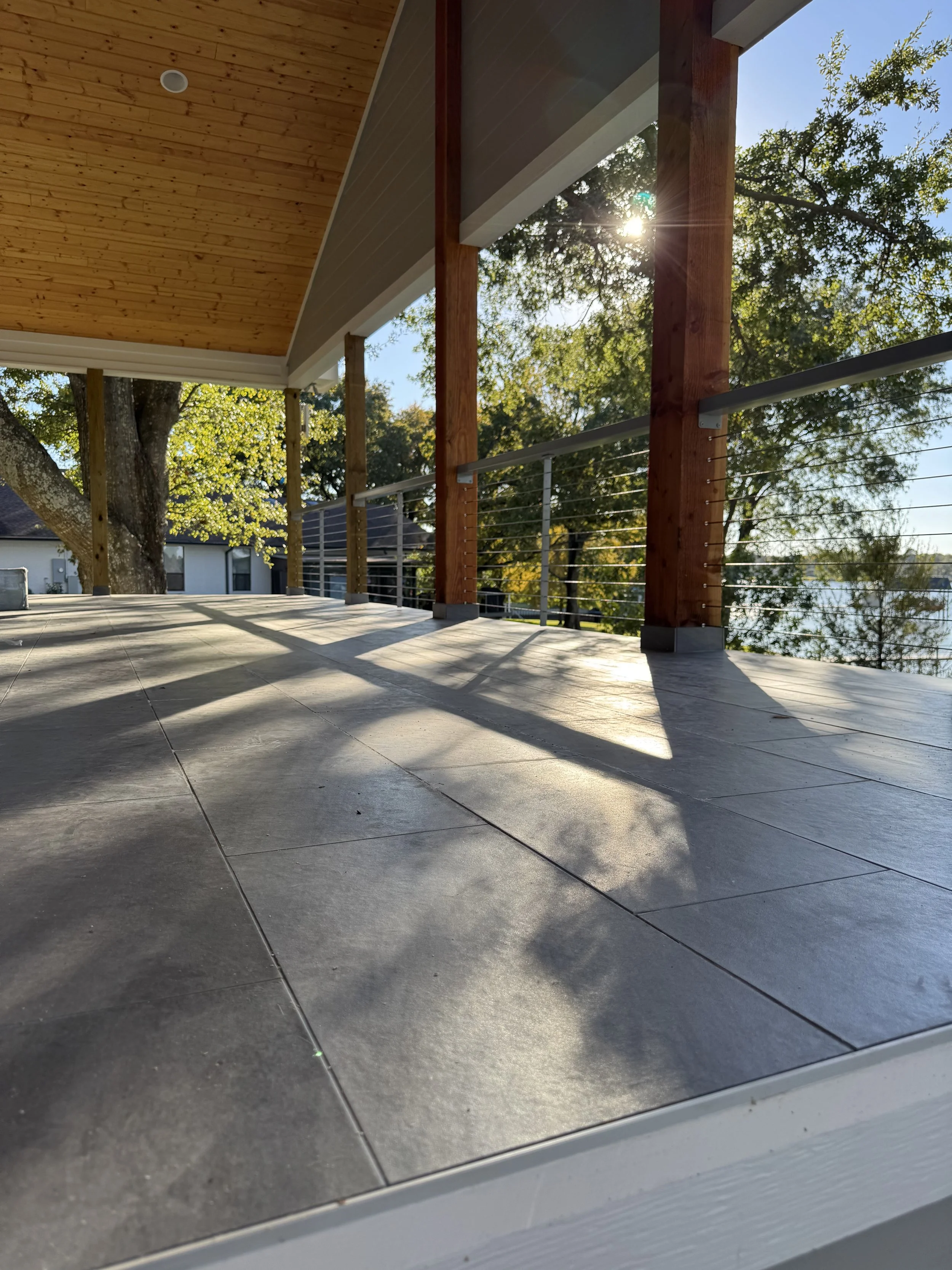 View of a balcony with tiled flooring, wooden railing with metal wires. 