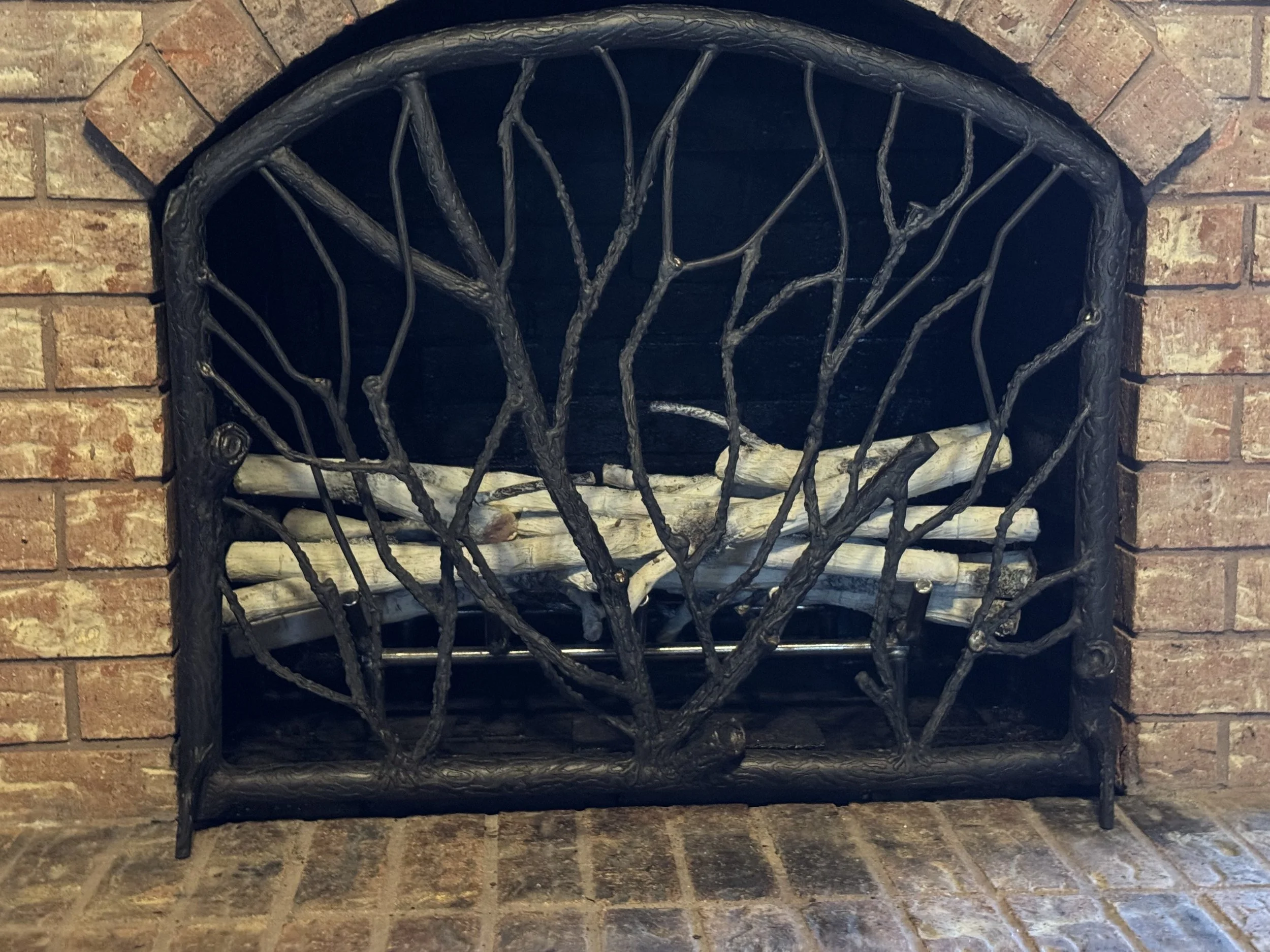 Decorative fireplace with a black metal frame designed to resemble tree branches.