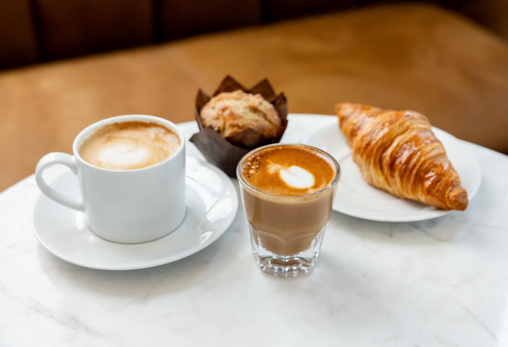 Coffee, cappuccino, muffin, and croissant on a white table