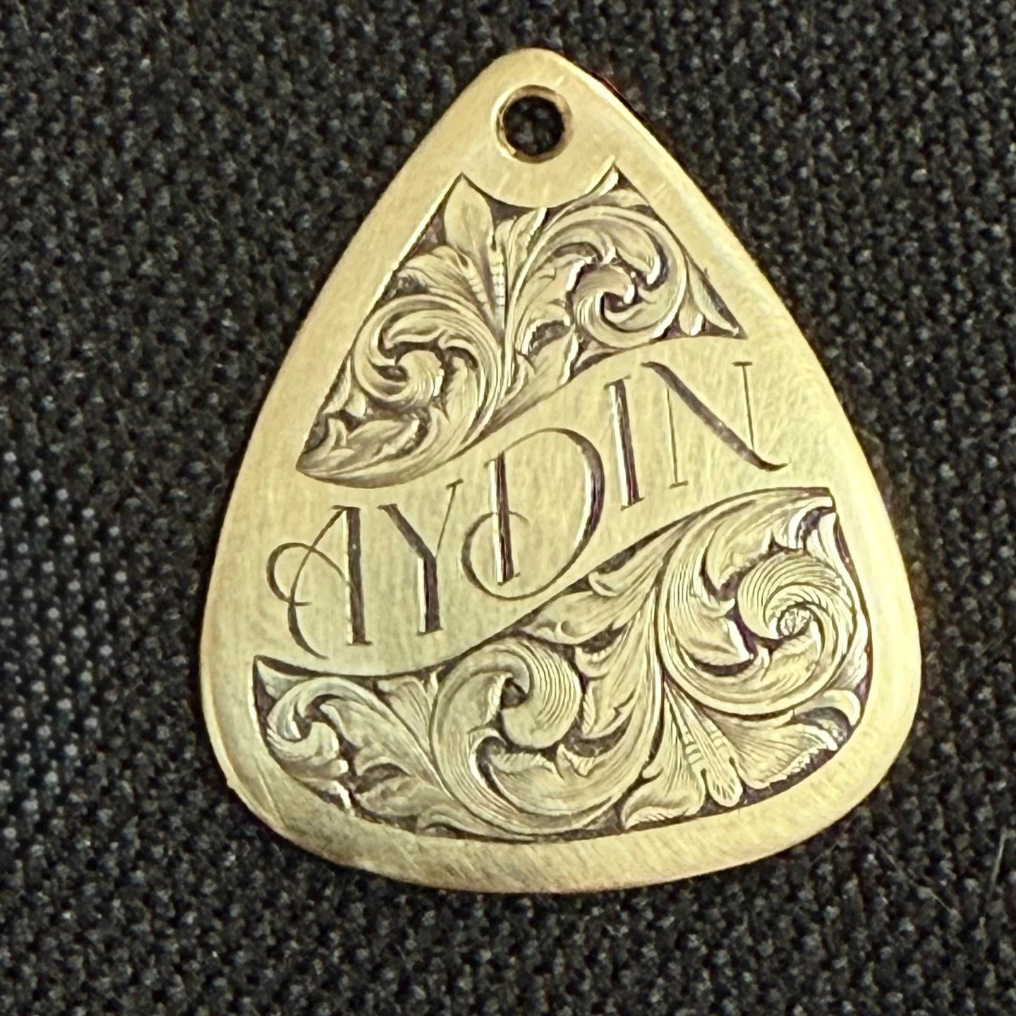 Custom engraved brass guitar pick pendant.#Engravedjewelry
#Engravedmetal
#Handmadeengraving
#Engravingartist
#Engravedartwork
#Engravedpendant
#Engravingbysage
#Scrollwork
#Bespoke
#Jewelry
#Handmade
#handengraver
#guitarpick