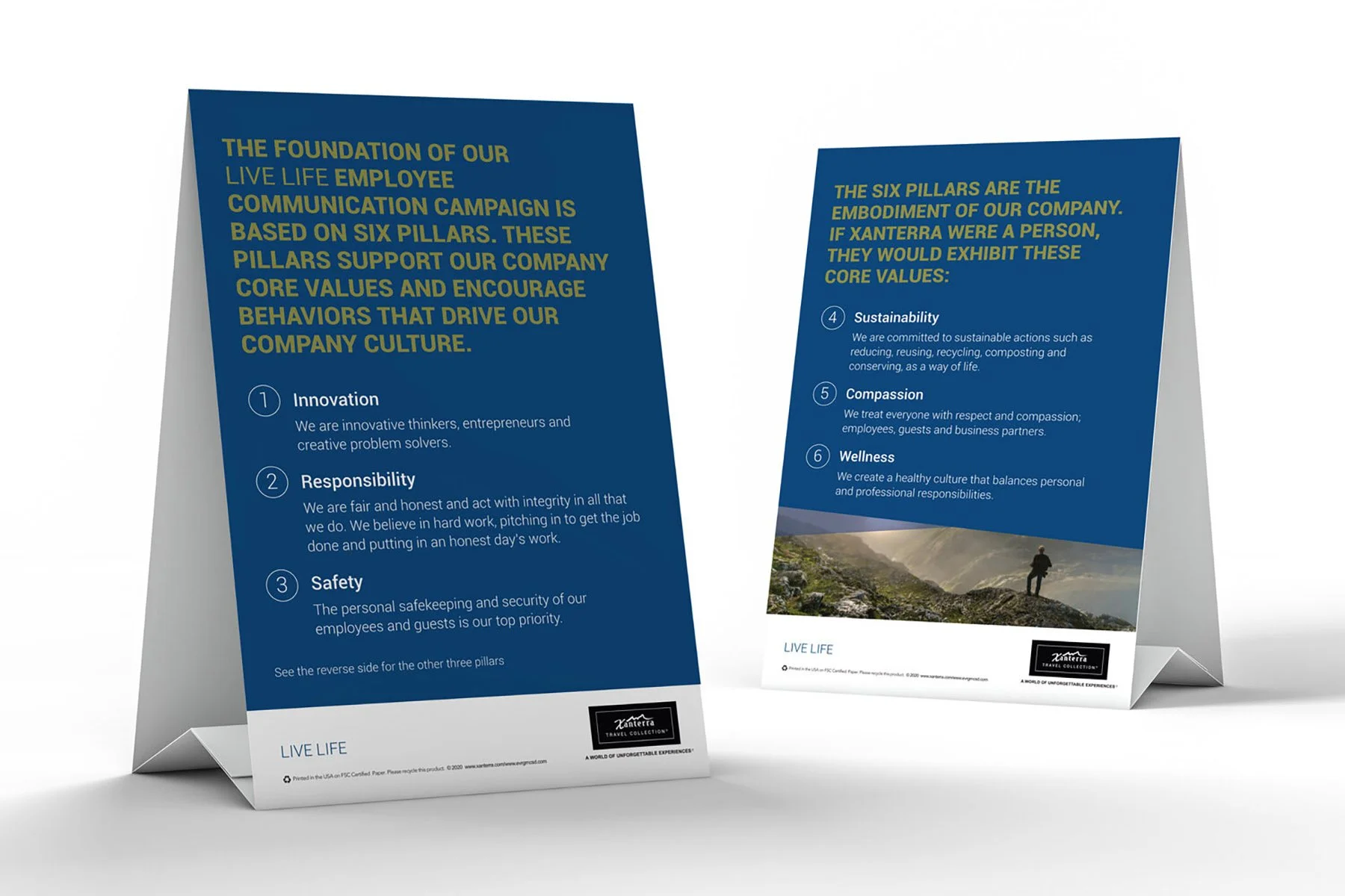 Two tabletop display cards featuring a company's core value pillars. The first card lists Innovation, Responsibility, and Safety. The second card lists Sustainability, Compassion, and Wellness. Both cards have blue background with white and yellow te