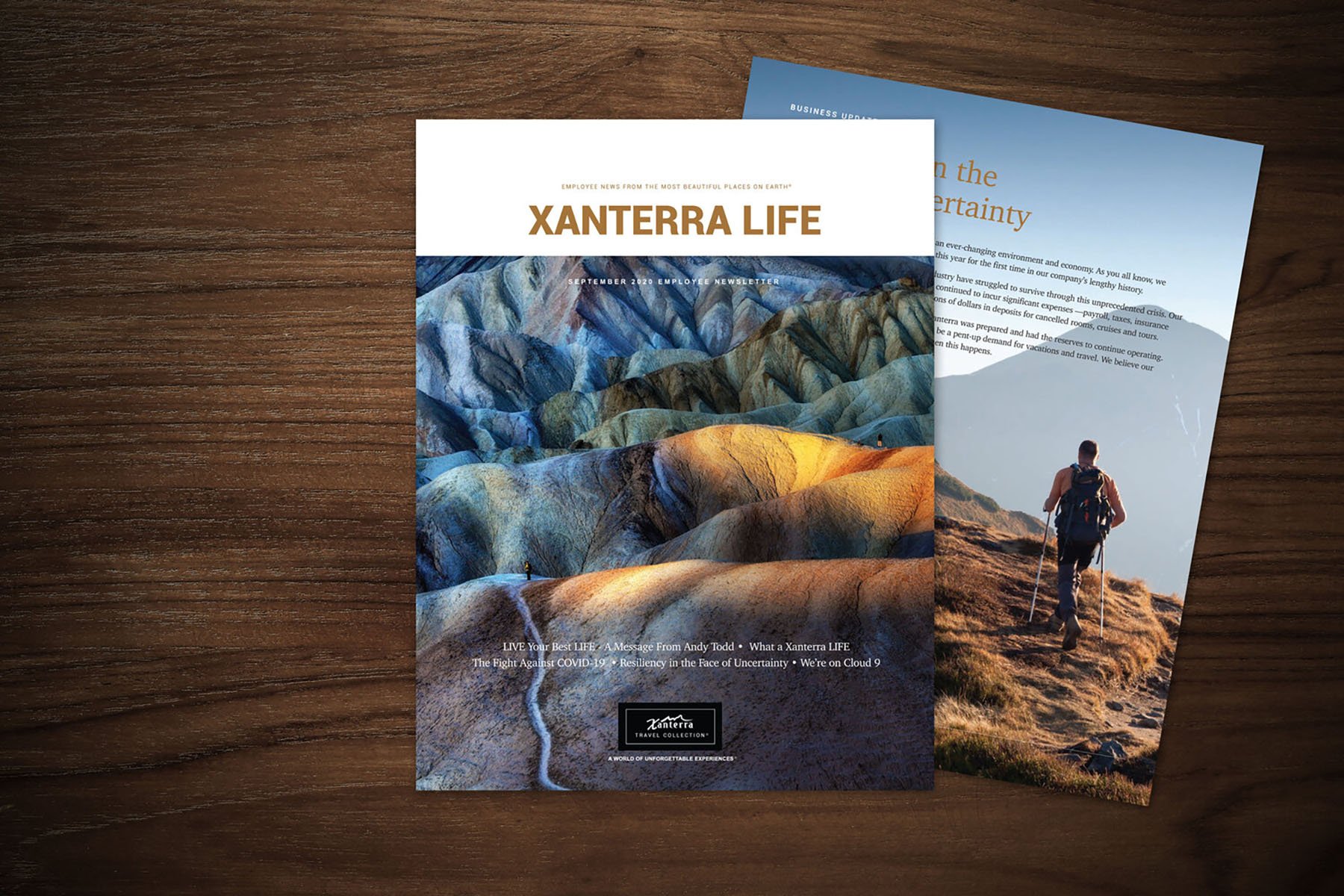 Two overlapping magazines on a wooden table. The top magazine, titled 'Xanterra Life,' features a colorful landscape image of hills. The second magazine shows a man hiking on a trail.