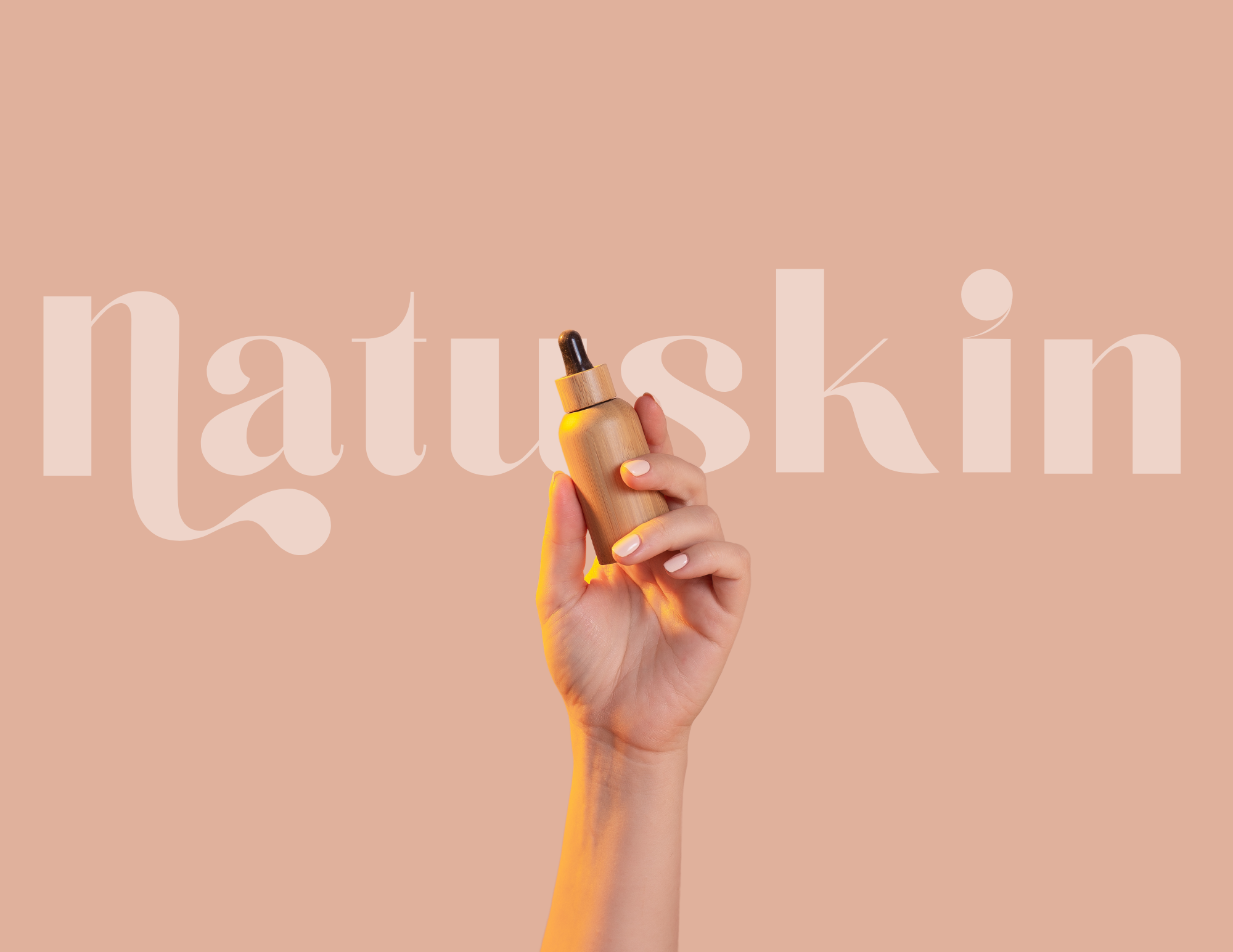 A hand holding a small wooden bottle with a dropper in front of a pink background with the word "natskin" written in large, light-colored text.