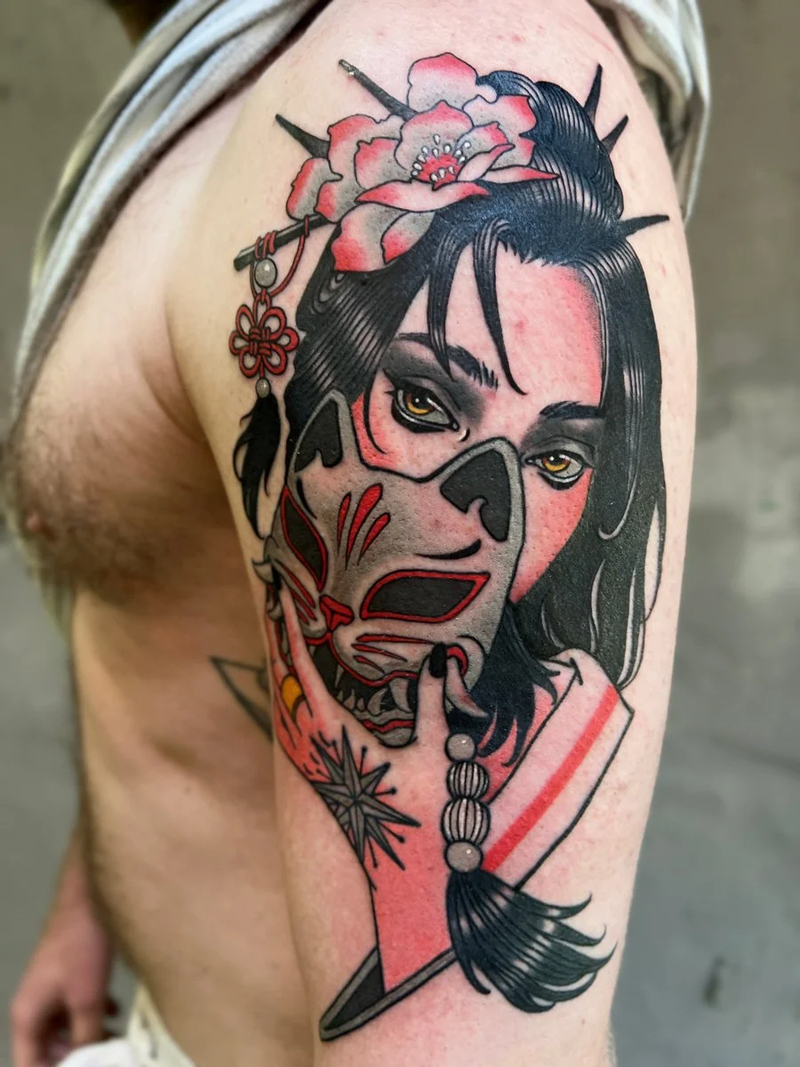 Tattoo of a woman with a painted face mask, Asian-style hair accessories, and flowers, combining elements of traditional and modern styles.