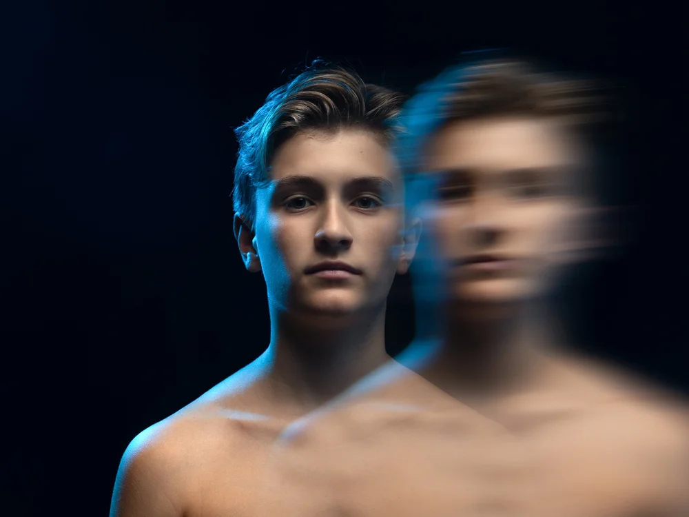 Portrait d'art en mouvement, double exposition d'un jeune homme sur fond bleu