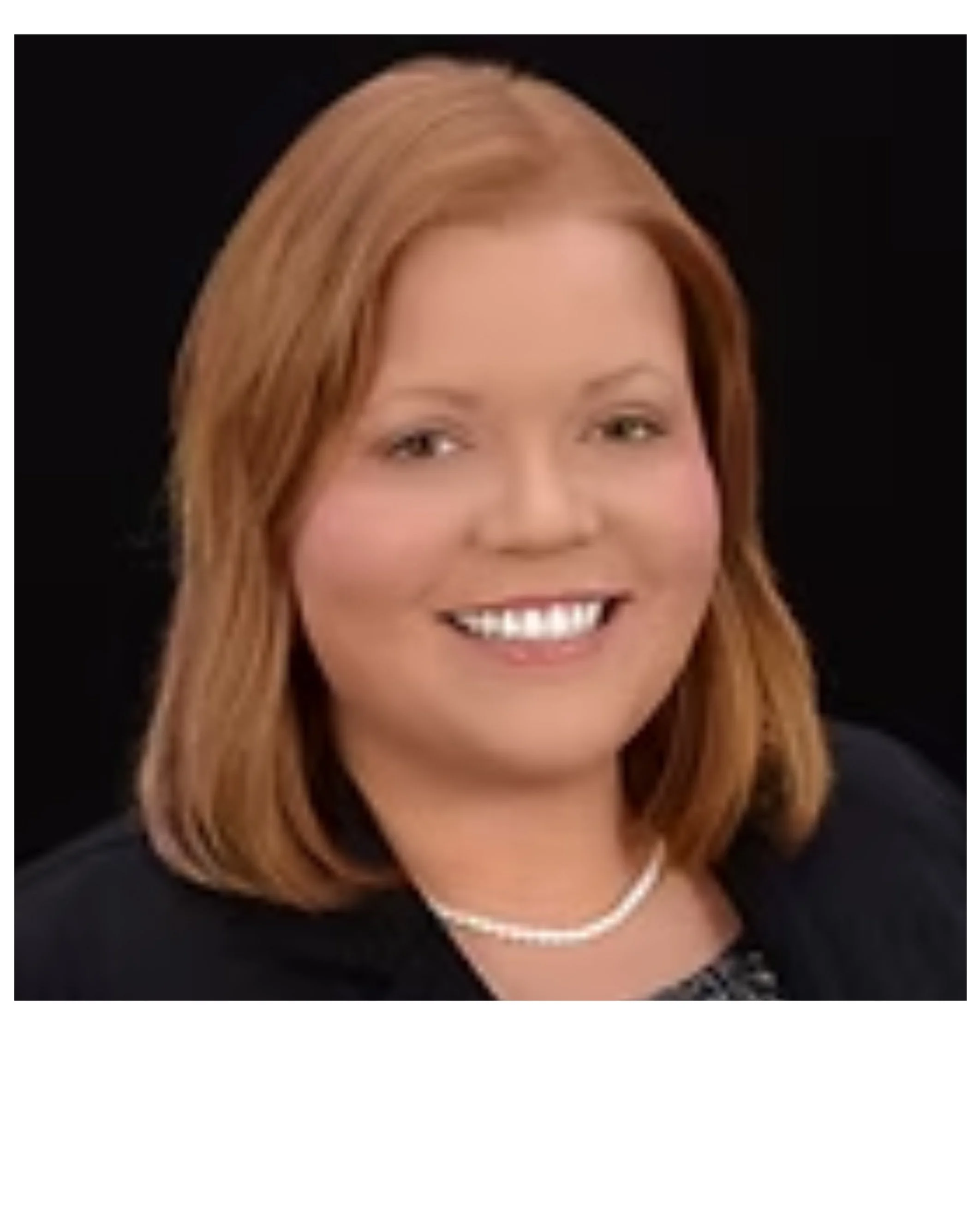 Headshot of a woman with shoulder-length red hair, smiling, wearing a black top and a pearl necklace
