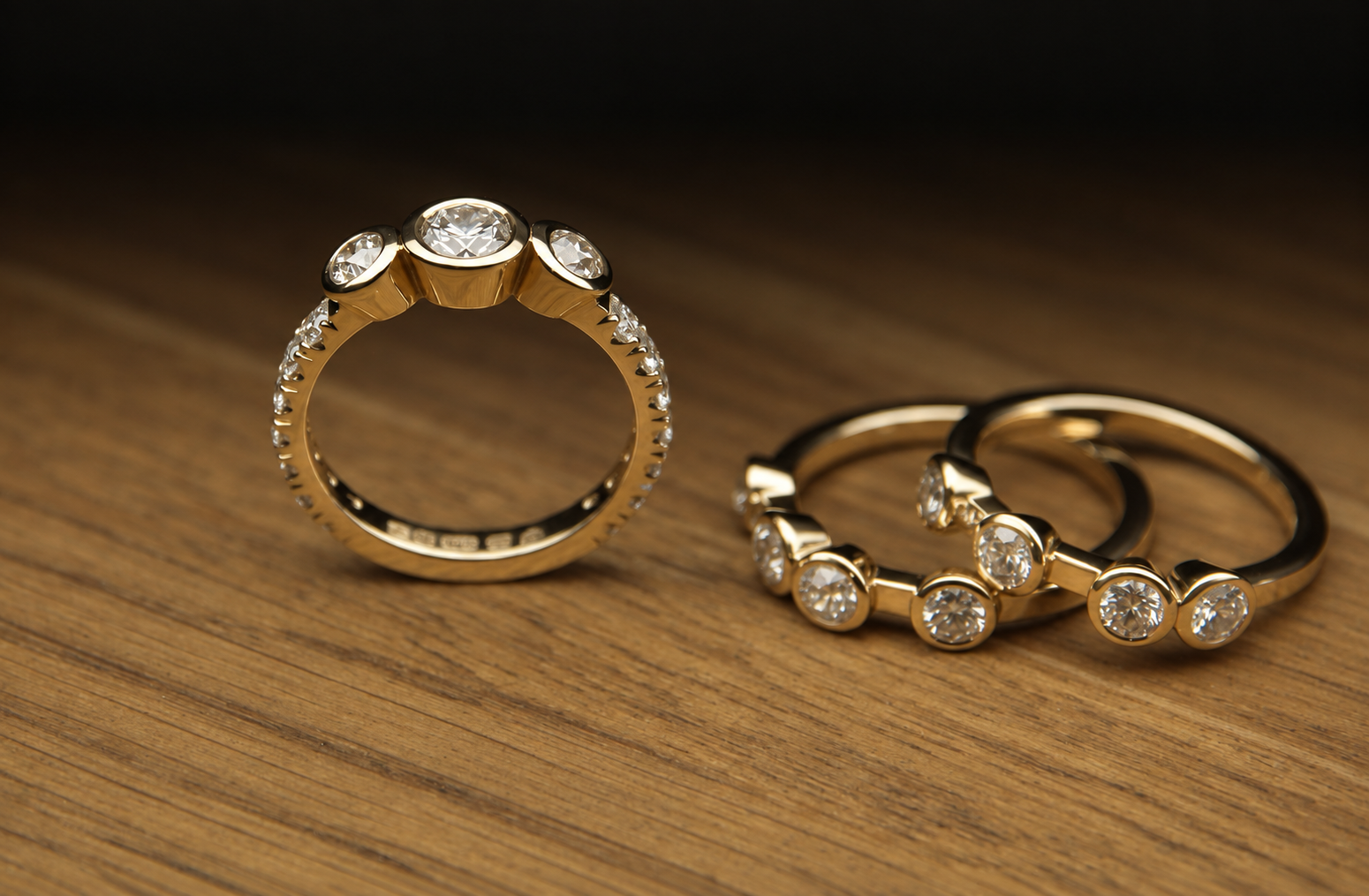 Three gold rings with diamonds on a wooden surface.