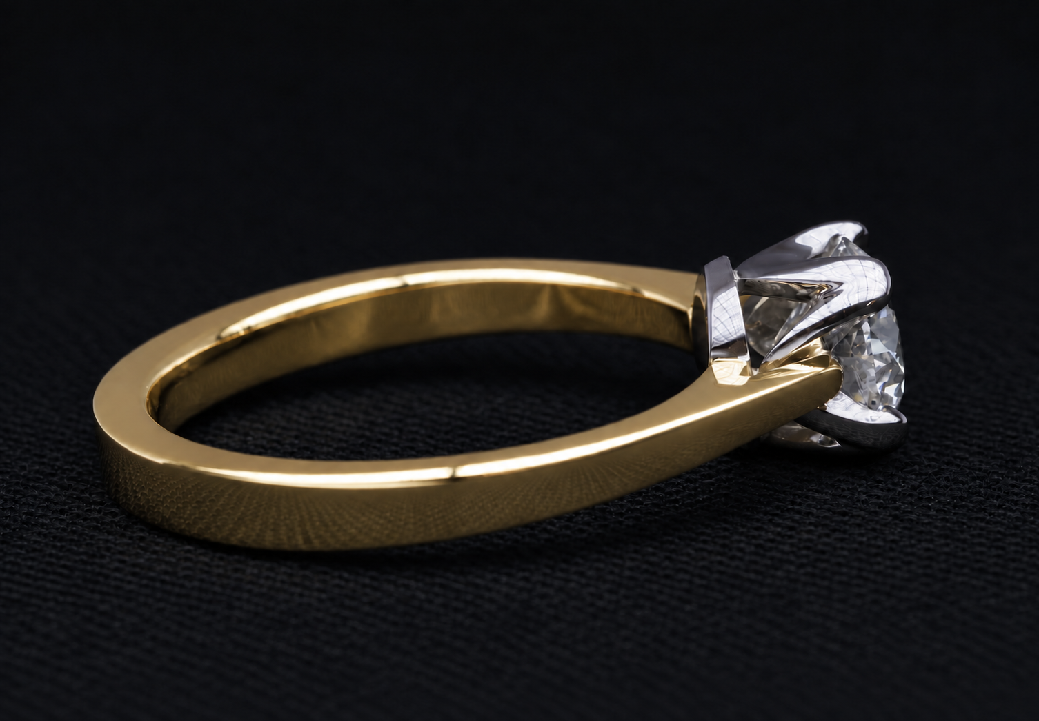 Close-up of a gold ring with a large diamond on black background.