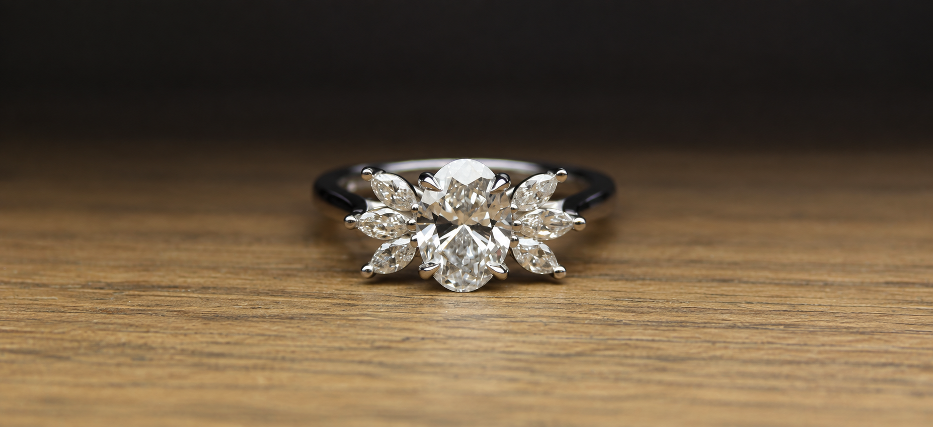 Diamond ring with a floral design on a wooden surface with a black background.