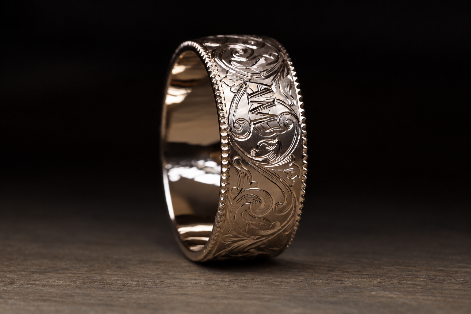 Close-up of a silver engraved ring with intricate floral scrollwork design