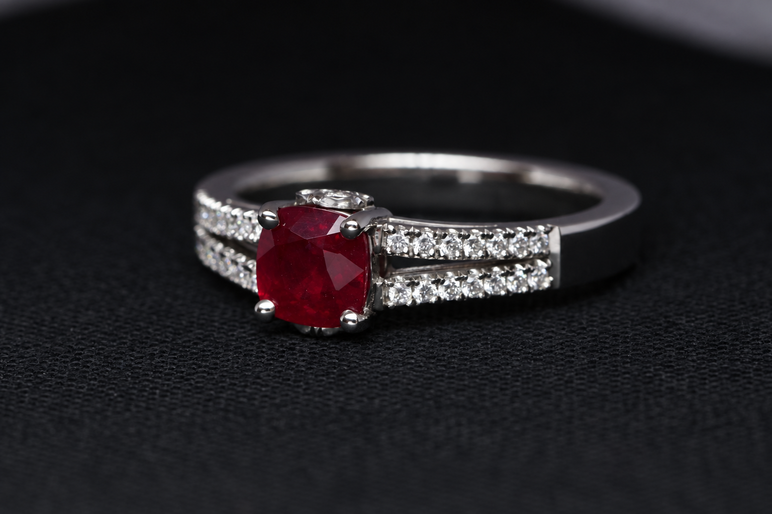 Silver ring with a large red gemstone and small diamonds on black background.