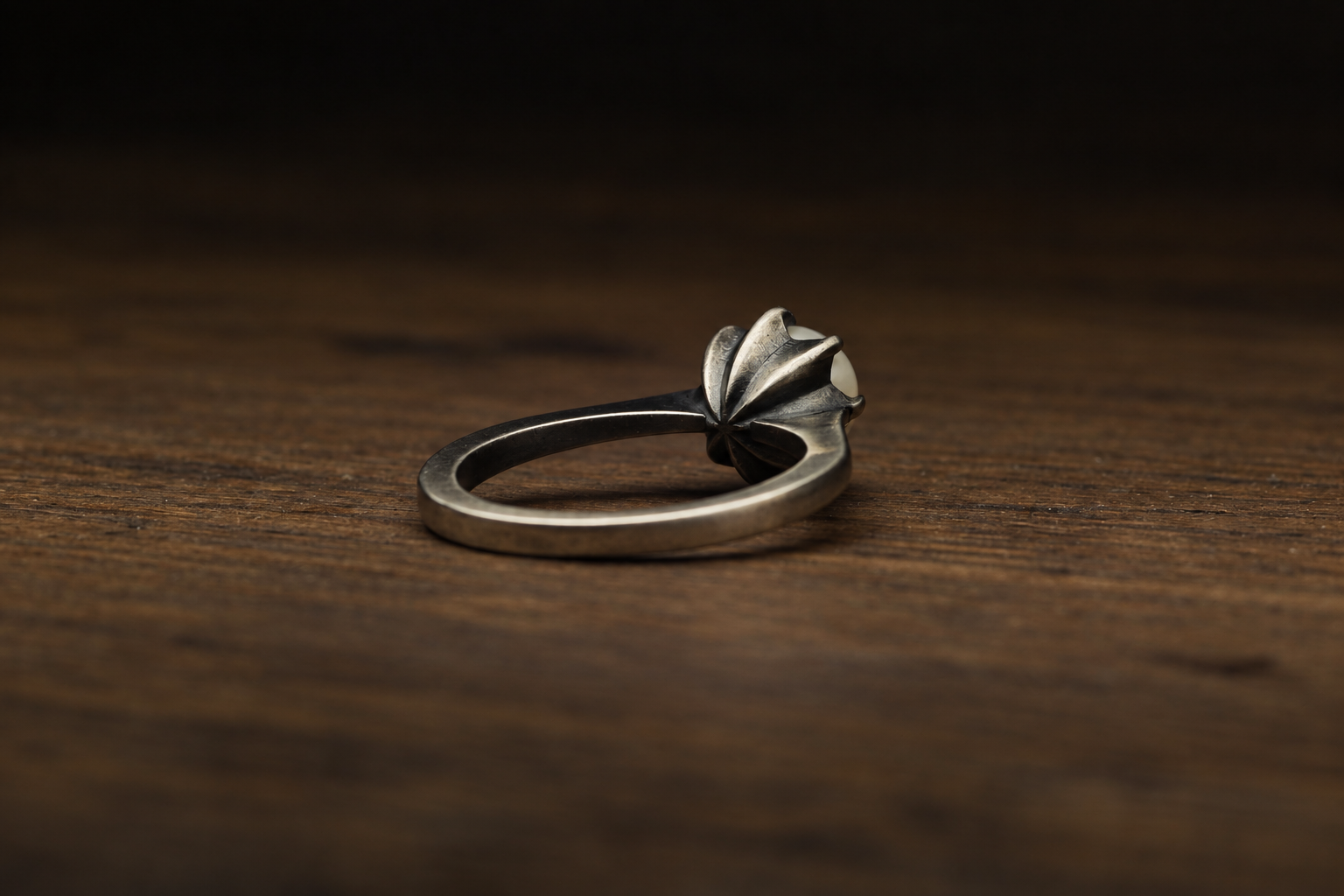 A silver ring with a floral design on a wooden surface.