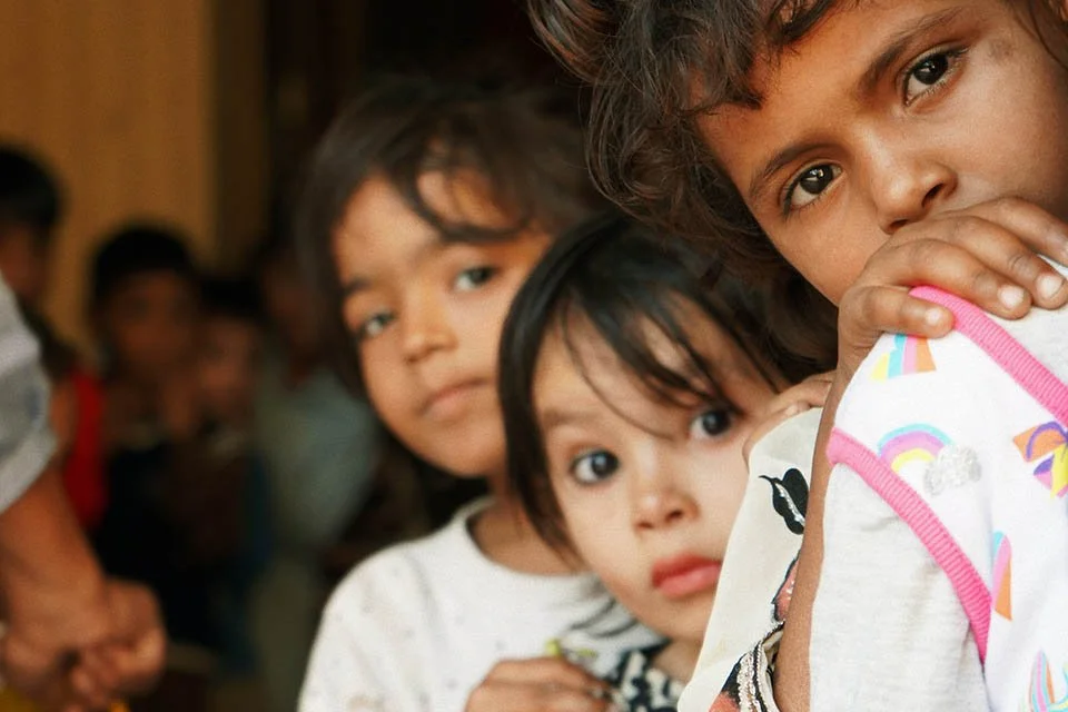 Three children standing in line, looking at the camera with serious expressions, close-up shot.