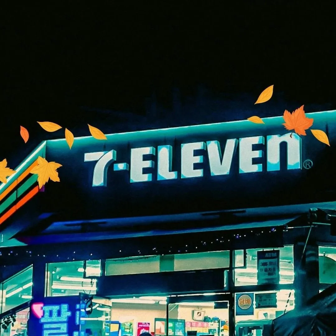 Neon sign for 7-Eleven store with autumn leaves overlay.