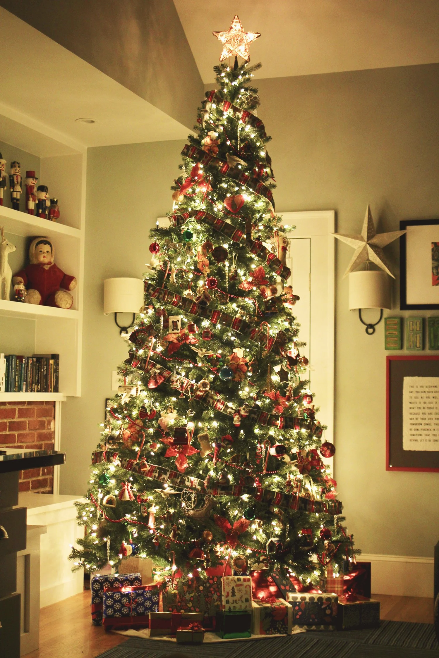 Decorated and illuminated Christmas tree with a star topper, surrounded by wrapped presents in a cozy living room.