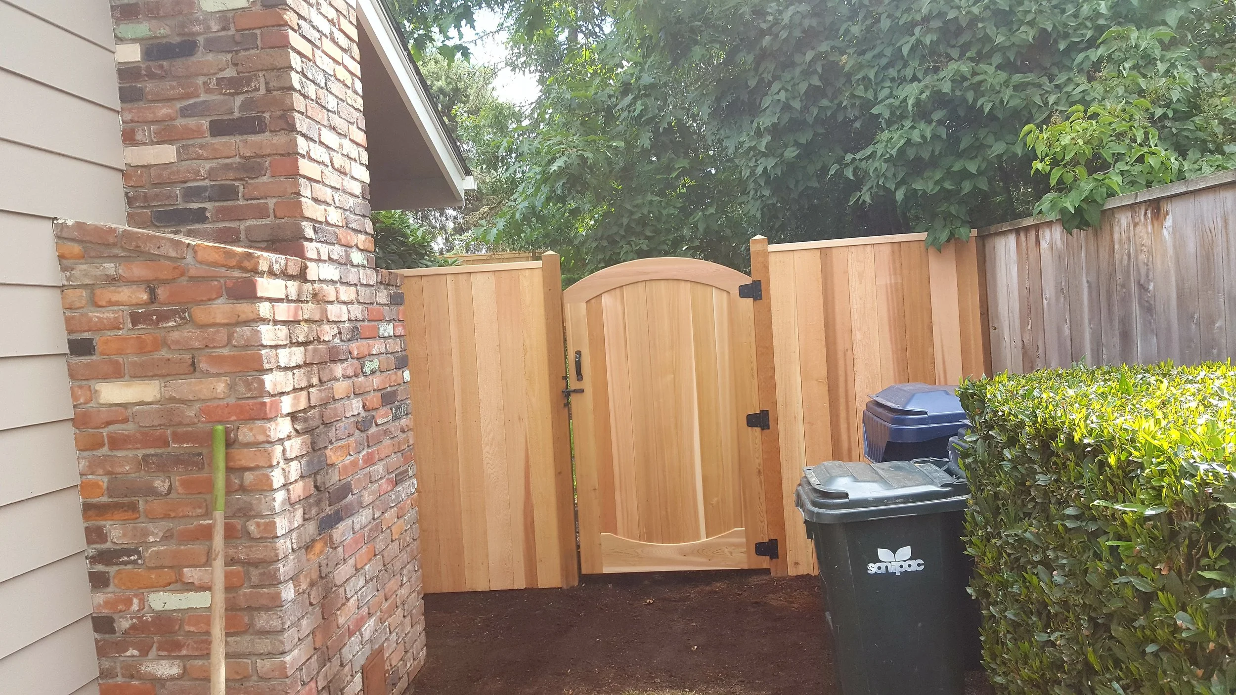 A custom arched cedar gate adds charm and functionality to the side yard.