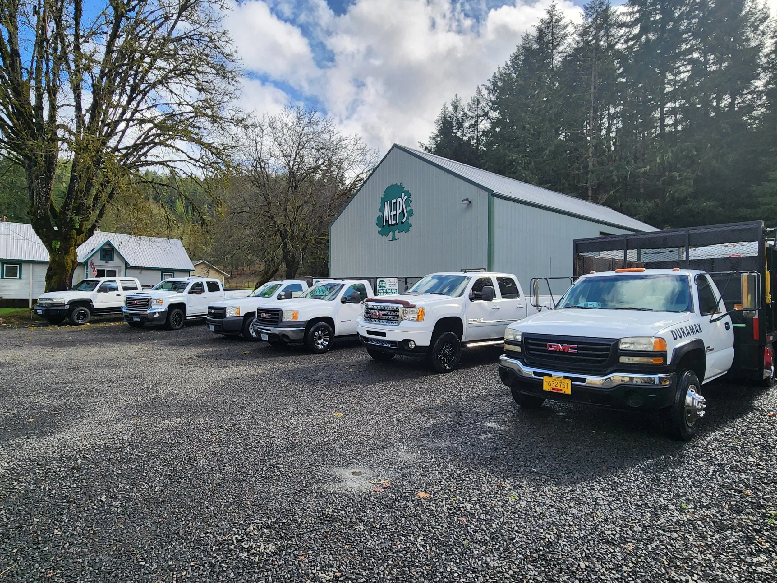 Line of white trucks in front of large shop