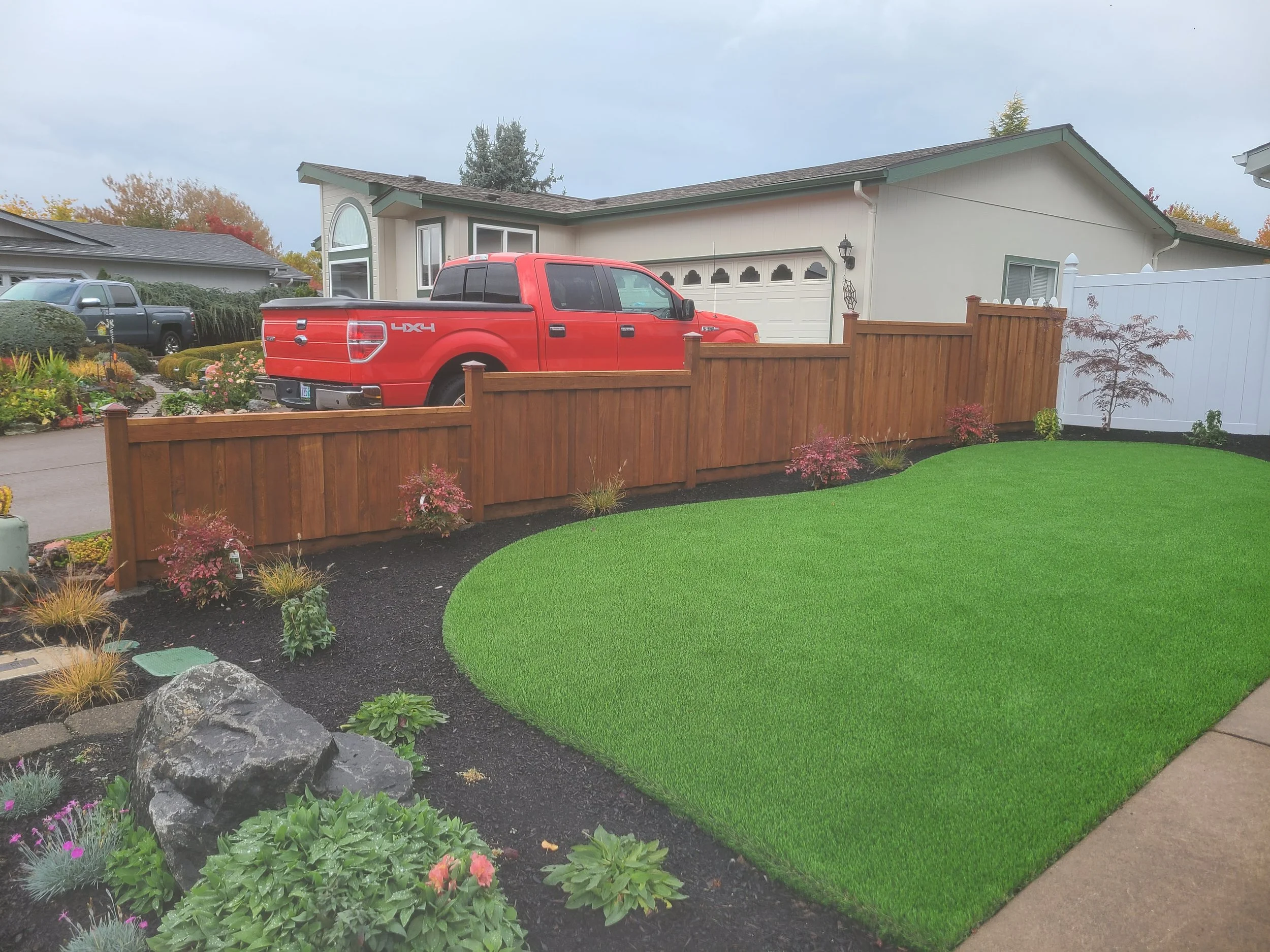 Stained cedar fence adds warmth and charm to a front yard landscape.