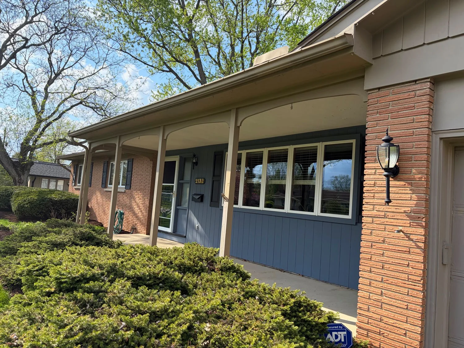 Before and after of a Columbus porch repaint with sage green shutters and brass light fixtures