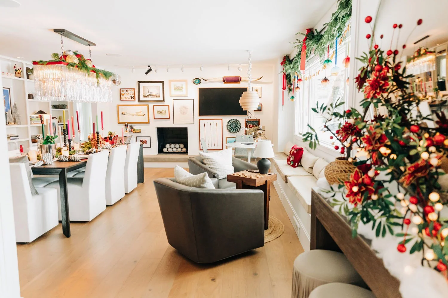 Open-concept living and dining room decorated for the holidays with garland, a window banquette, and layered conversation seating