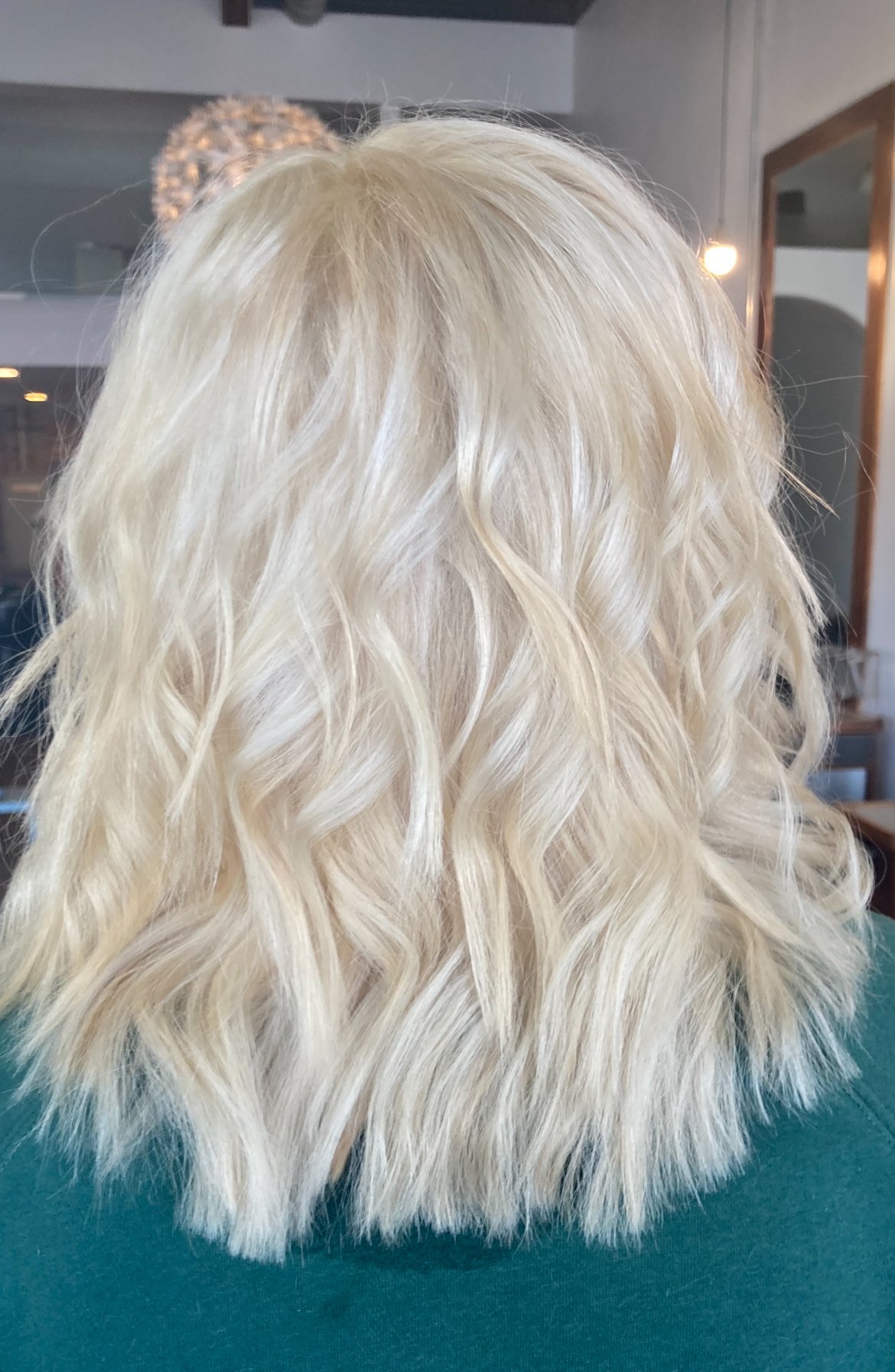Back view of layered, wavy blond hair color done with Bleach and Tone