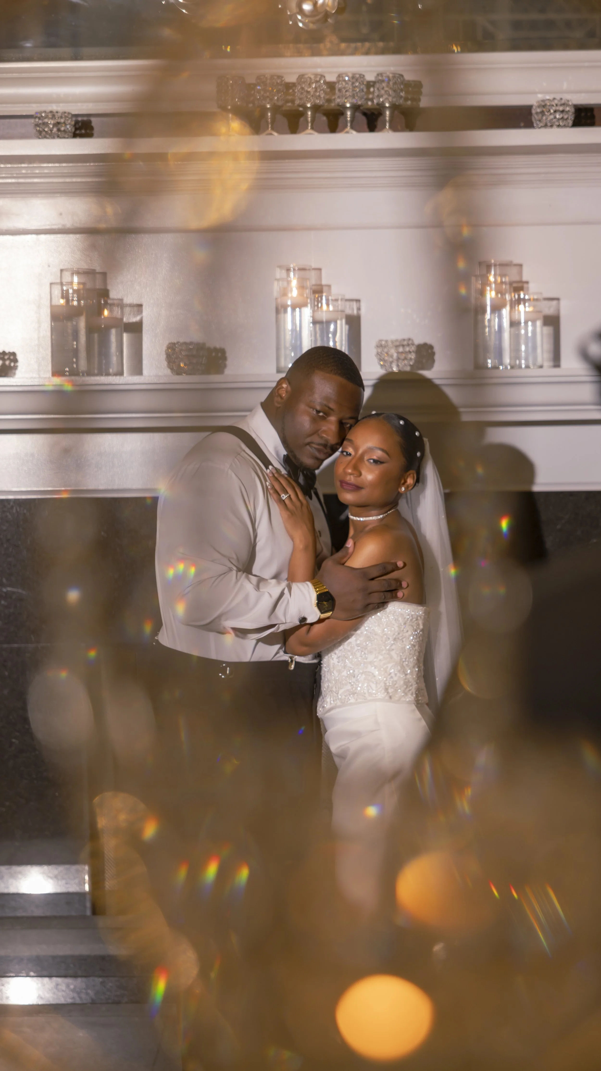 A newlywed couple, a man in a white shirt and a woman in a white wedding dress, embracing on the dance floor at their wedding reception.