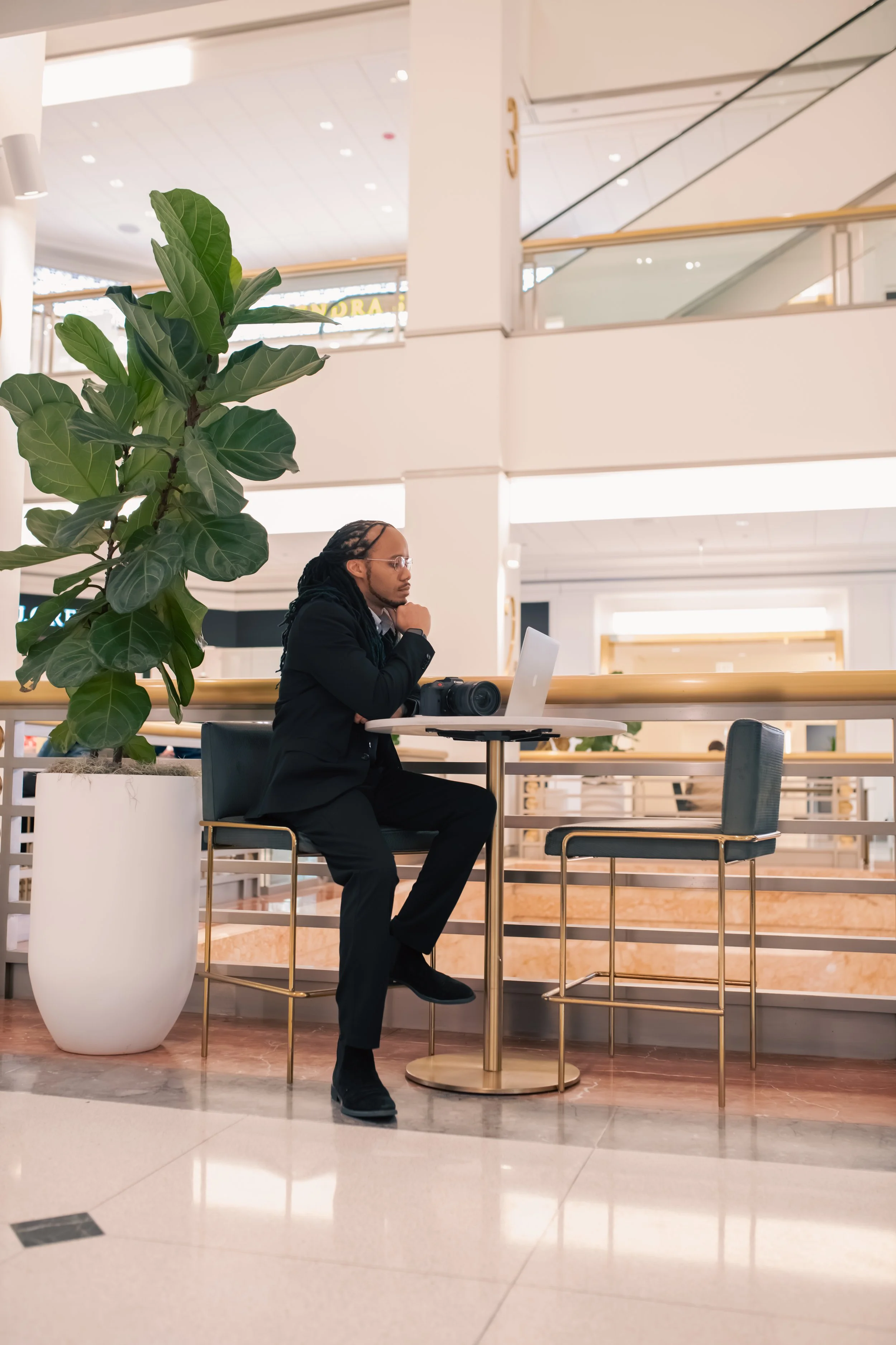 A person sitting at a table, working on a laptop with a camera beside them.