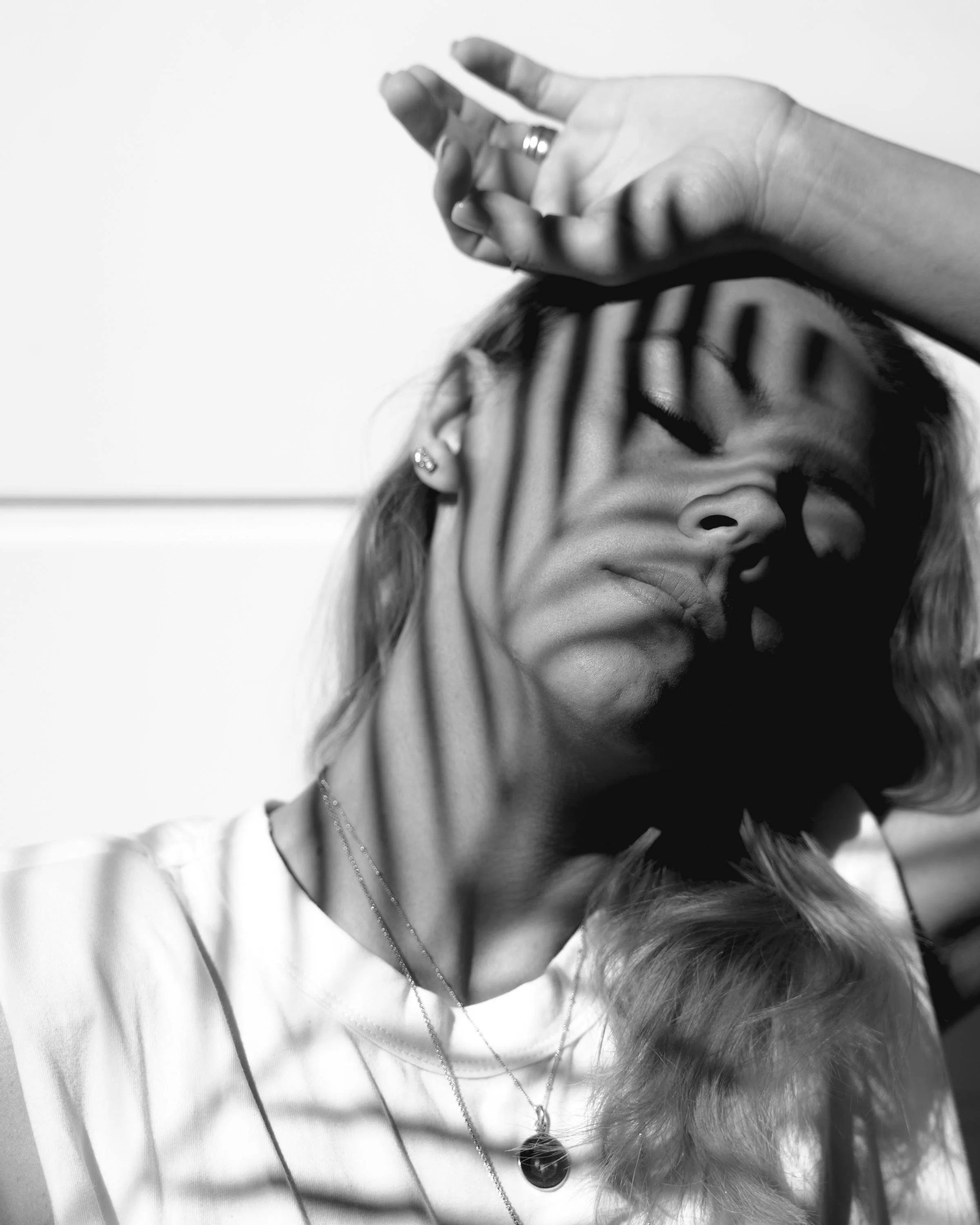 Close-up of a woman with eyes closed and leaf shadows representing Brainspotting therapy at Mental Lift