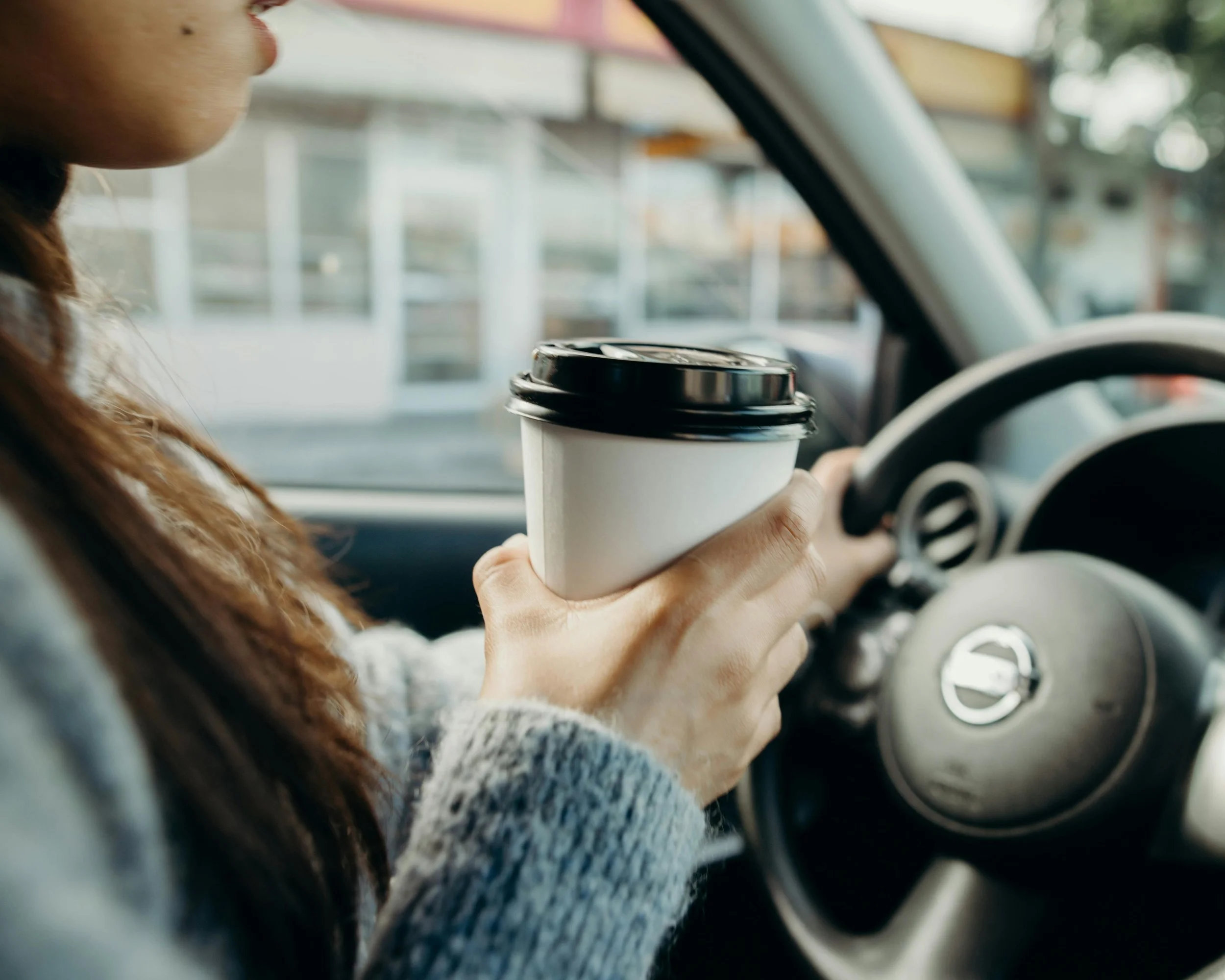 High‑functioning woman sitting in her car with a coffee, appearing calm on the outside but carrying internal stress and nervous system overwhelm.