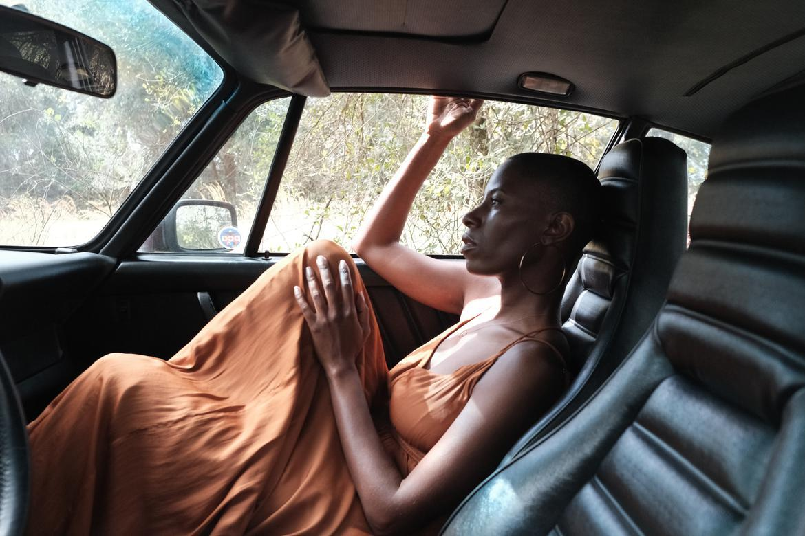 Black woman sitting quietly in a parked car during a reflective moment.