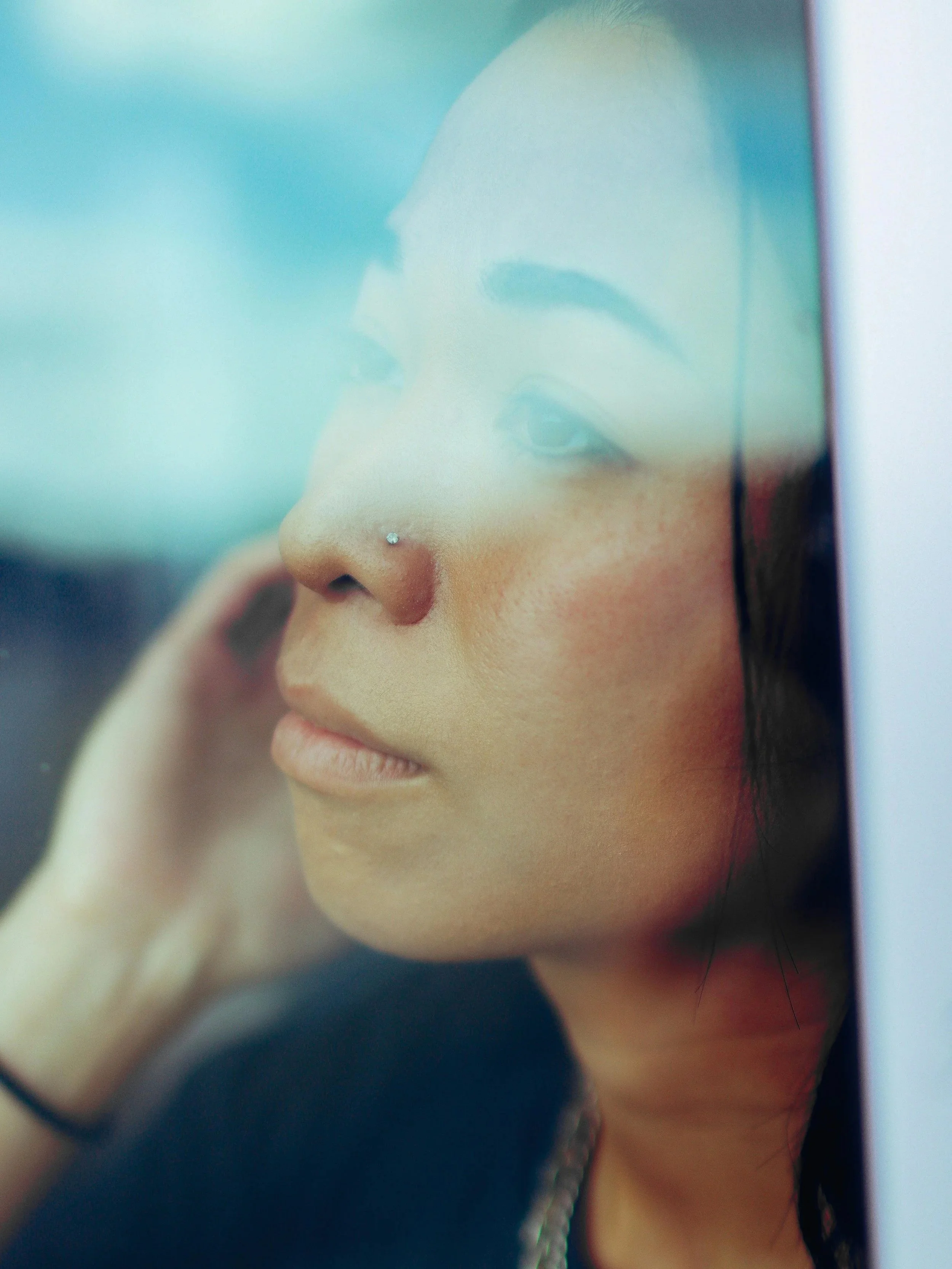 Asian woman looking out a window with a thoughtful expression, symbolizing emotional overwhelm and the need to protect peace