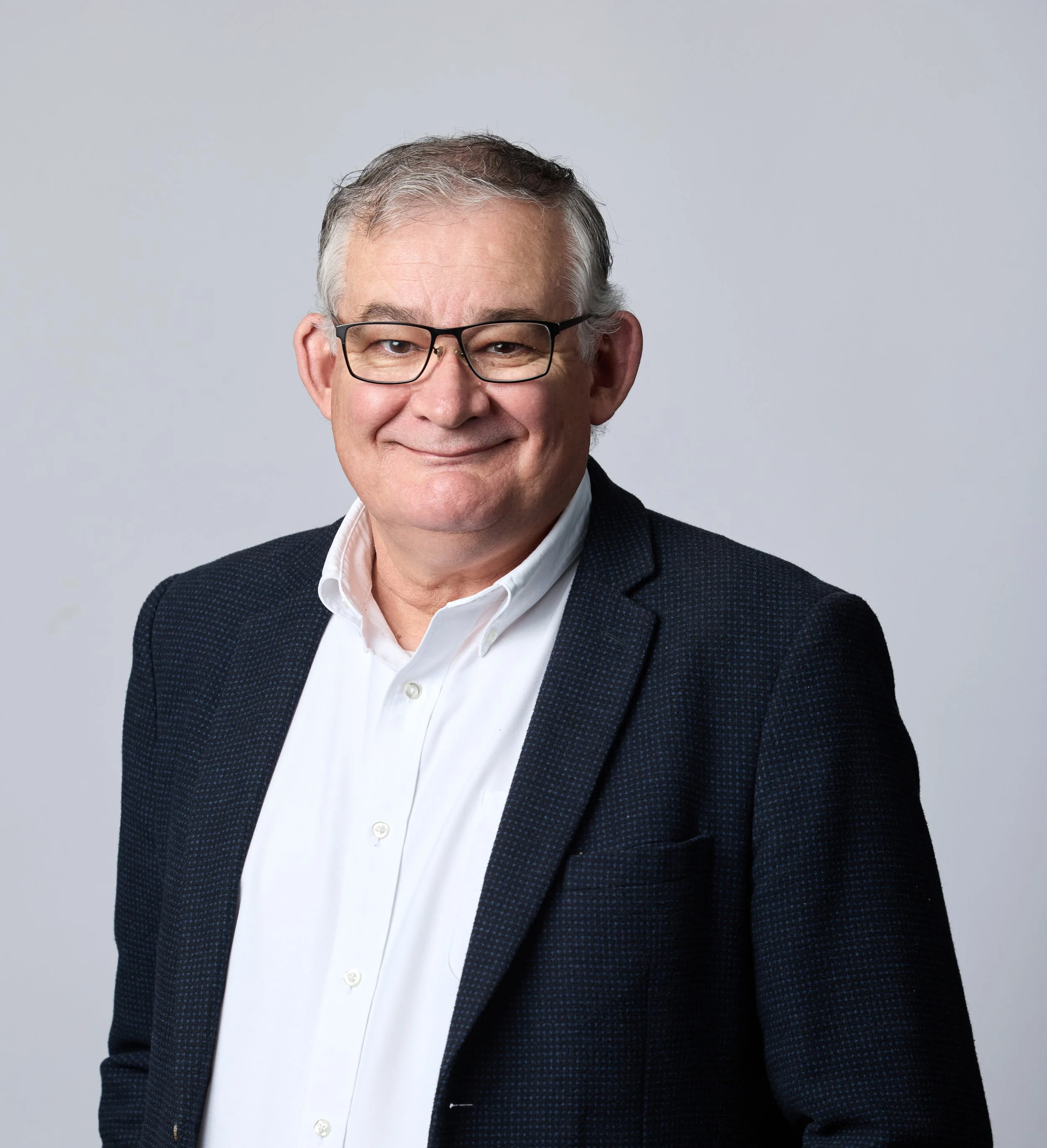 Smiling person with glasses and a blue suit and white shirt