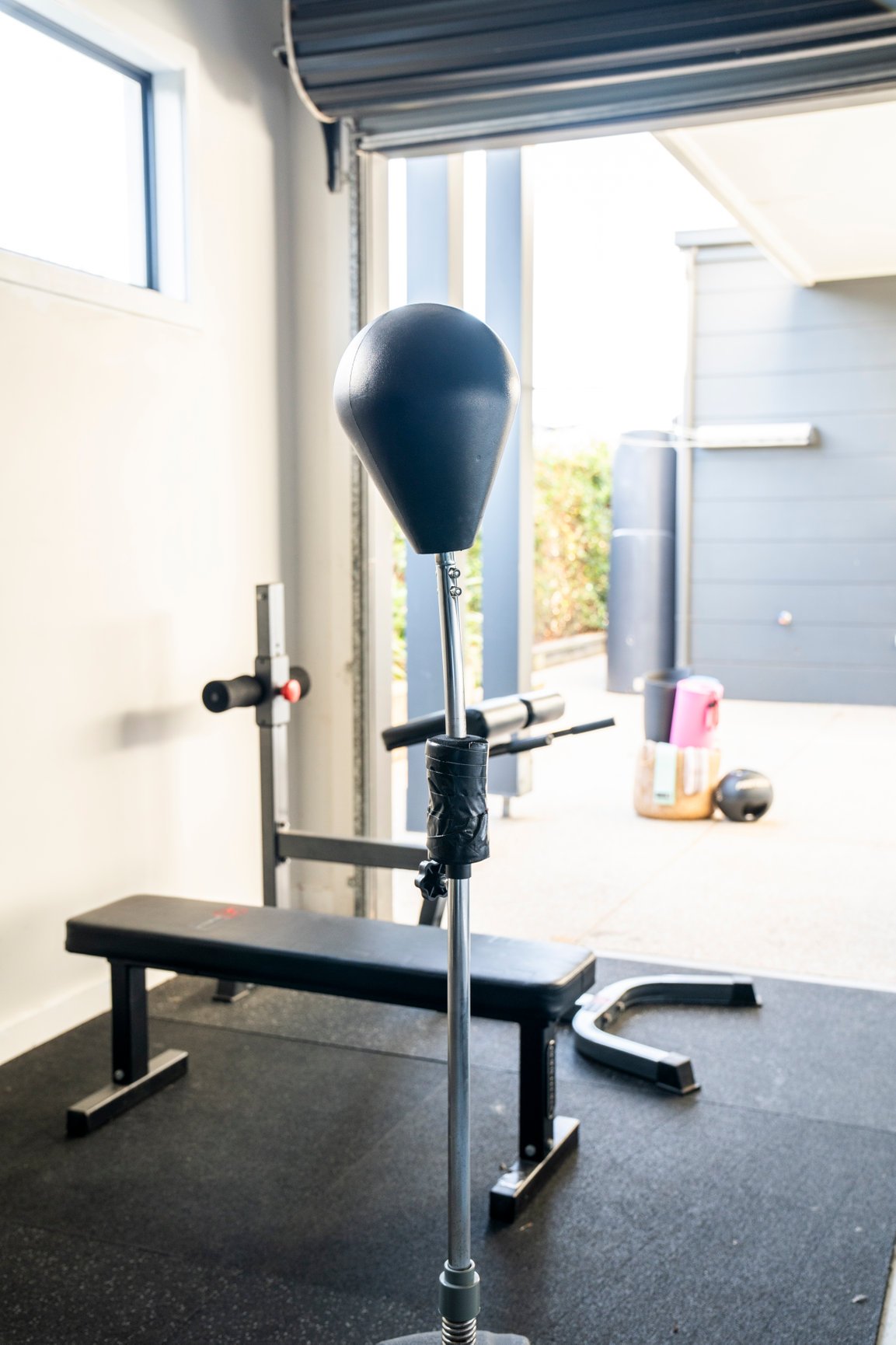 Home gym with punching bag, exercise bench, and fitness equipment.