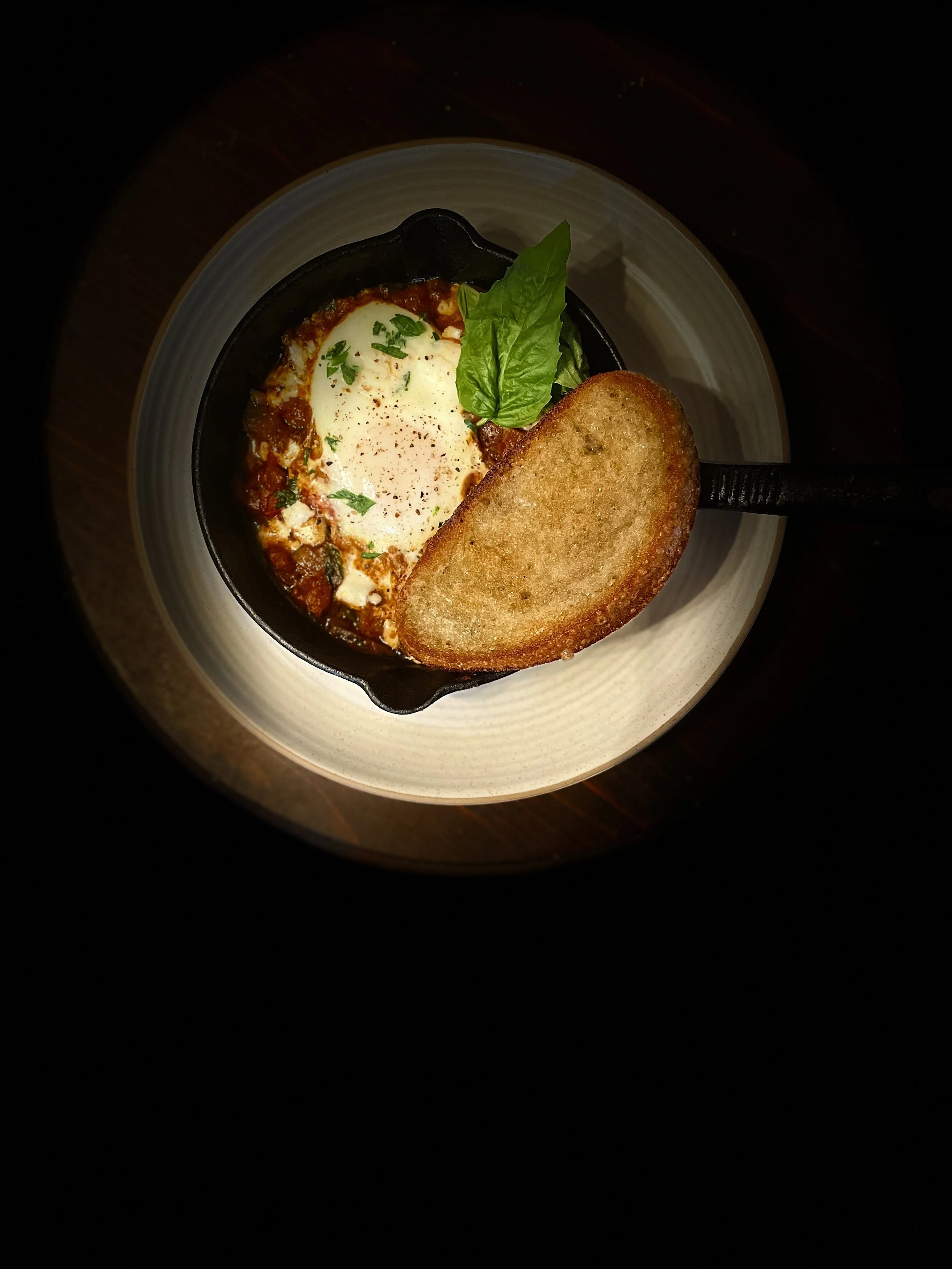 shakshuka. a moroccan spiced tomato stew with poached egg and basil in a skillet. a beautiful brunch catering classic. monmouth county new jersey caterer private dining chef near me