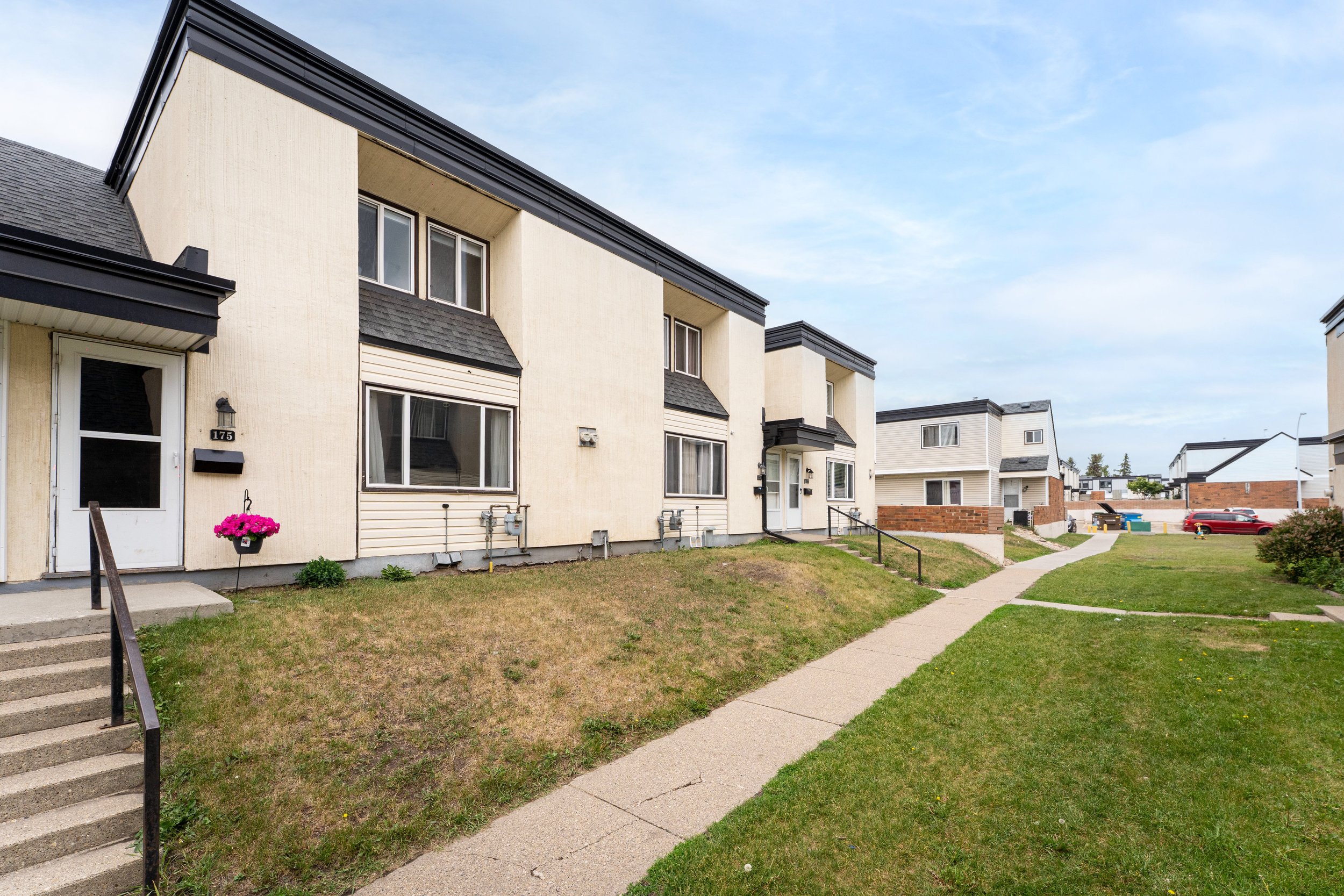 Side view of a modern property with grassy pathway and clear sky.
