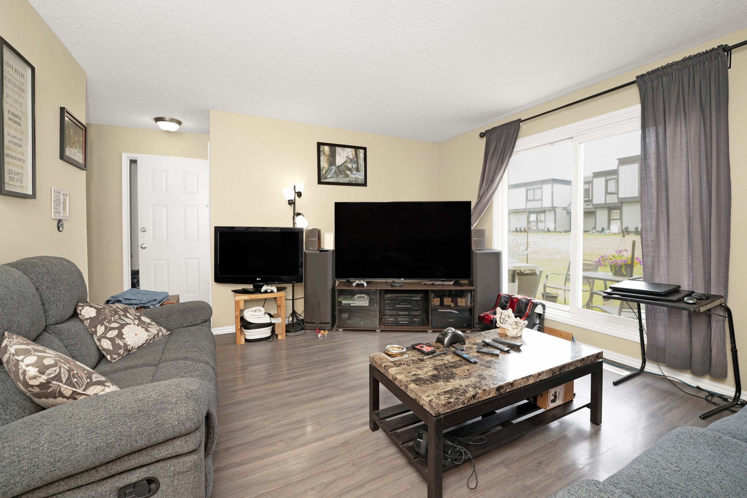 Spacious living room in a rent to own home with a large TV and sofa.