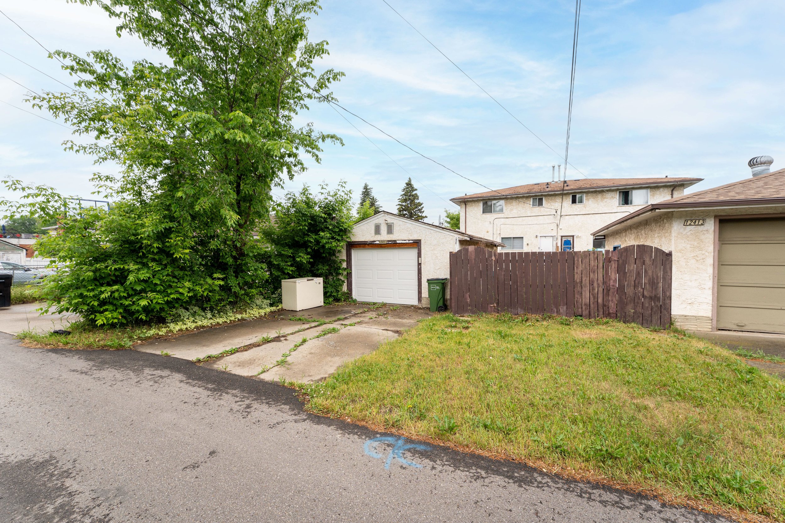 Street view of a rent to own house with a driveway and green surroundings.