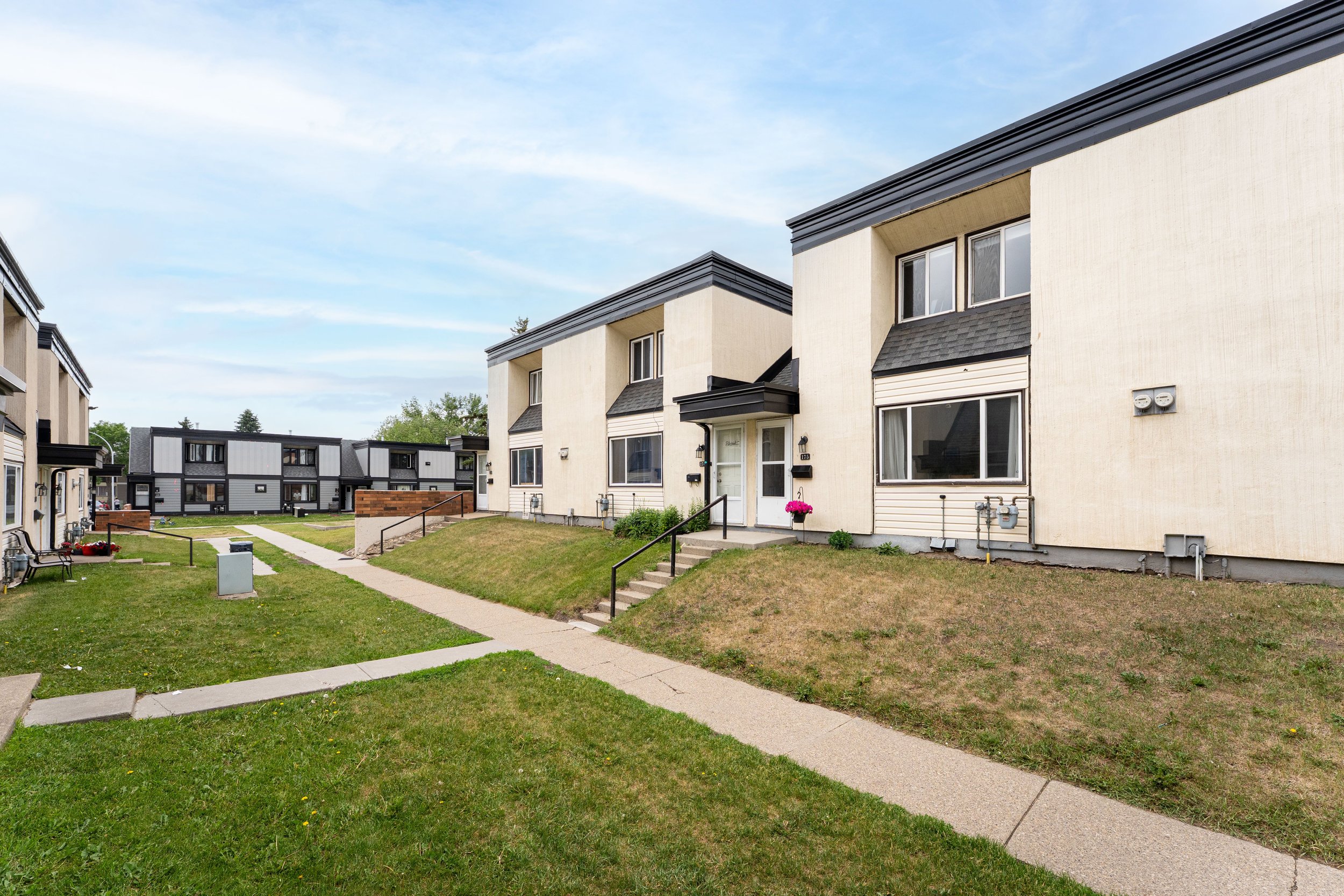 Row of townhouses with lush lawns in a peaceful neighborhood.