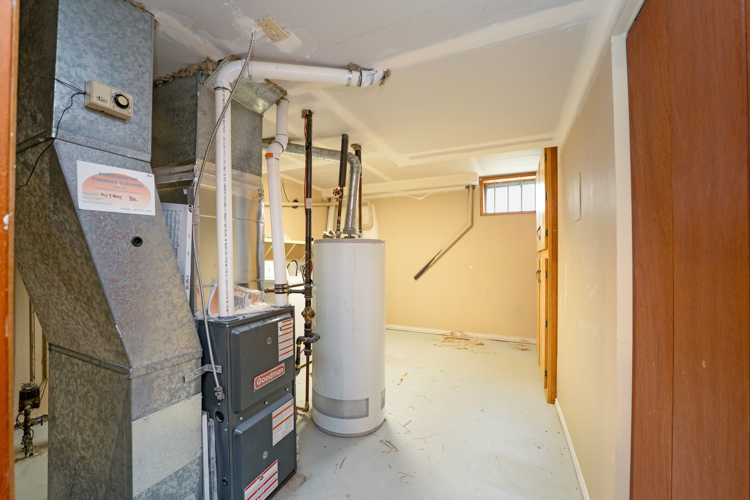 Residential basement with HVAC and water heater equipment, unfinished walls, and small window.