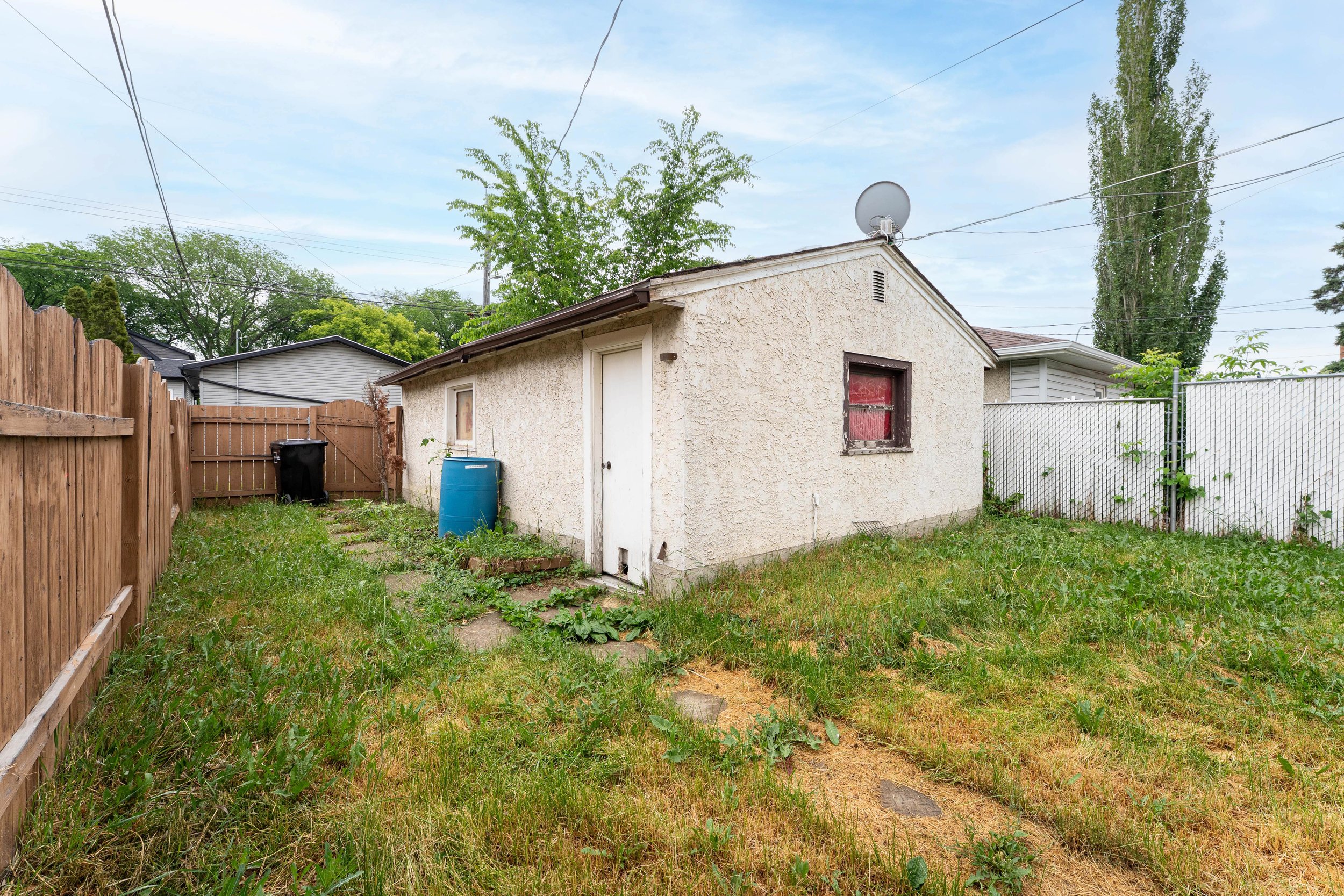 Rear perspective of a rent to own home with a wooden fence and greenery.