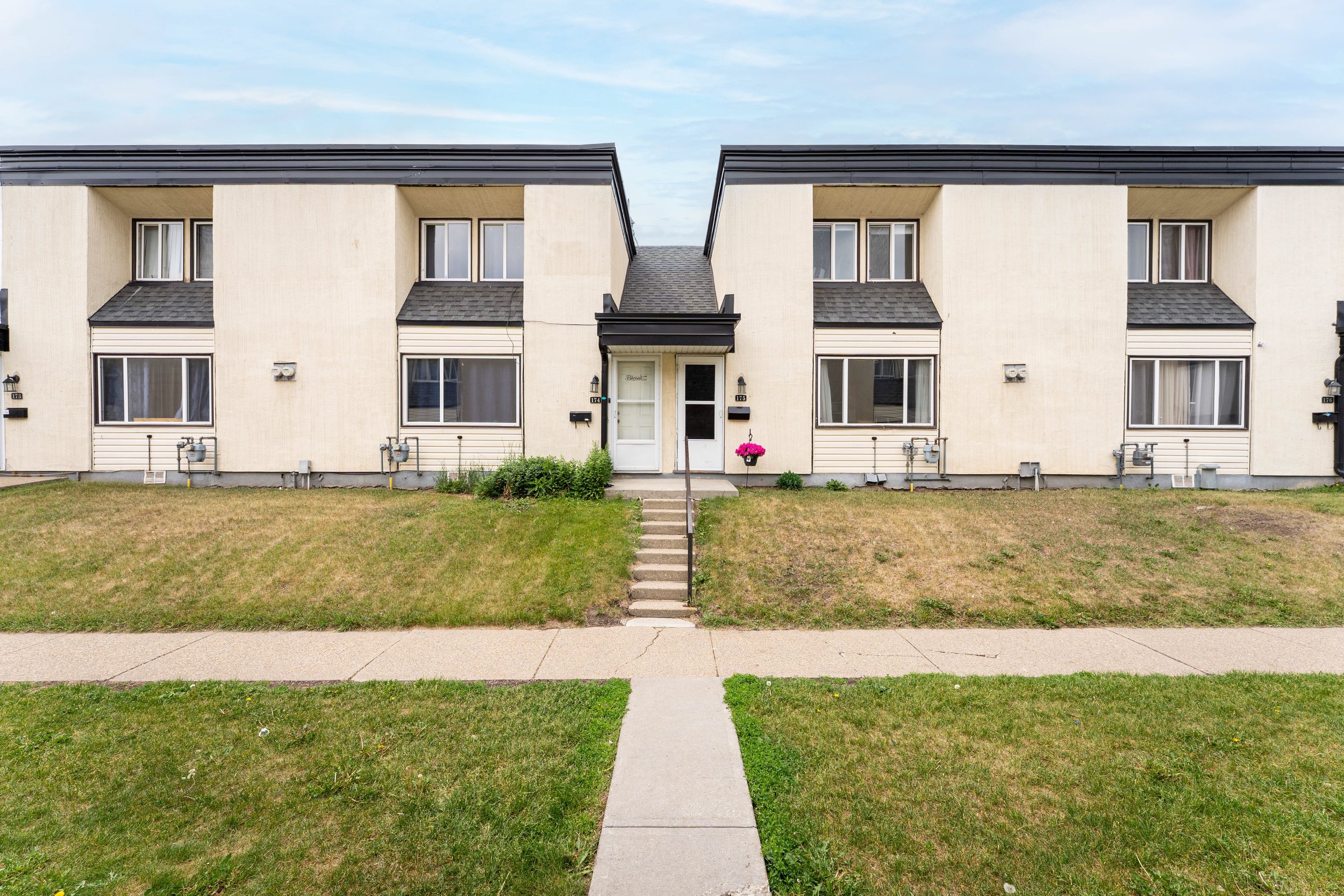 Front entrance of a rent to own multi-unit building with a well-maintained walkway.