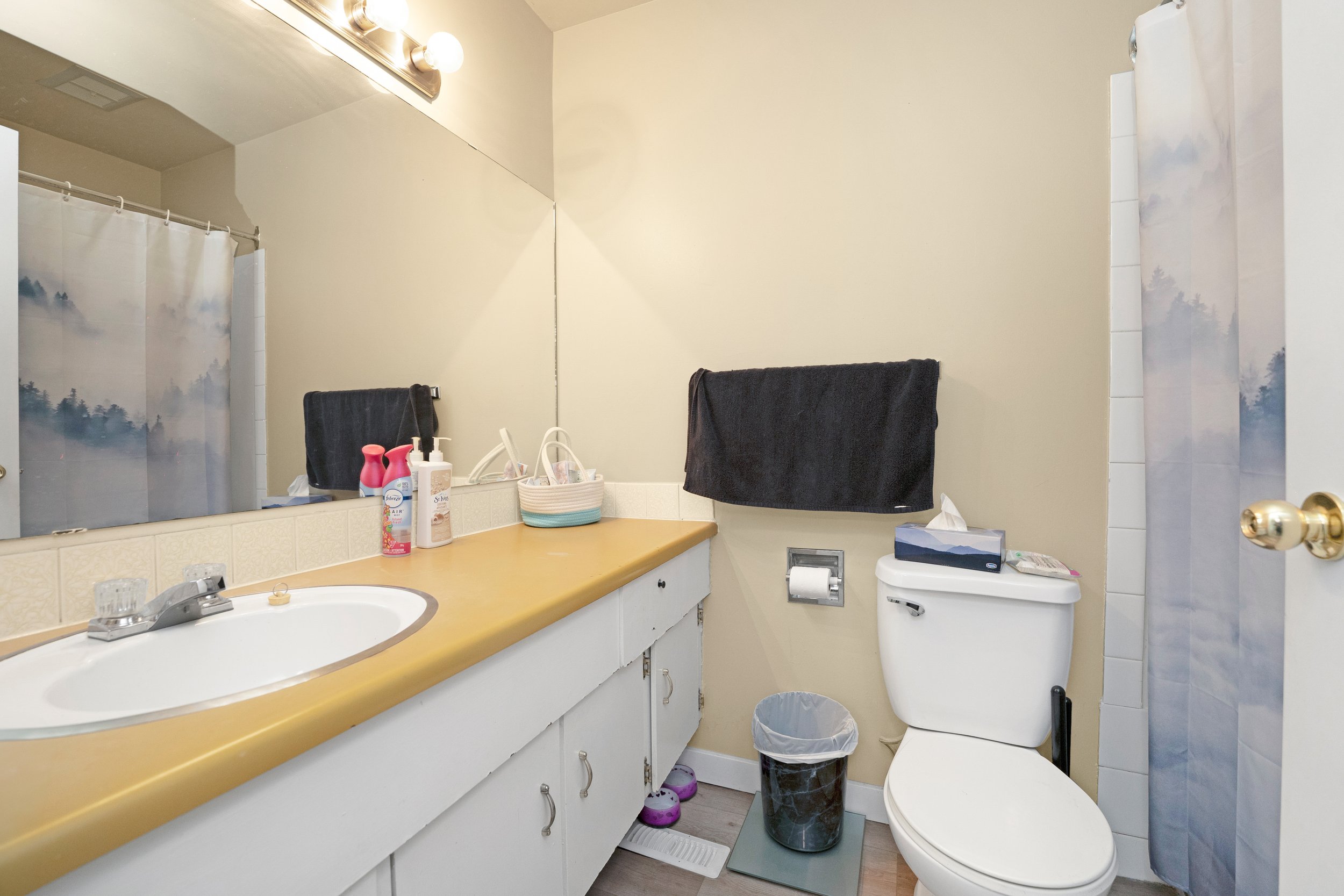 Clean bathroom with a sink, toilet, and countertop storage.