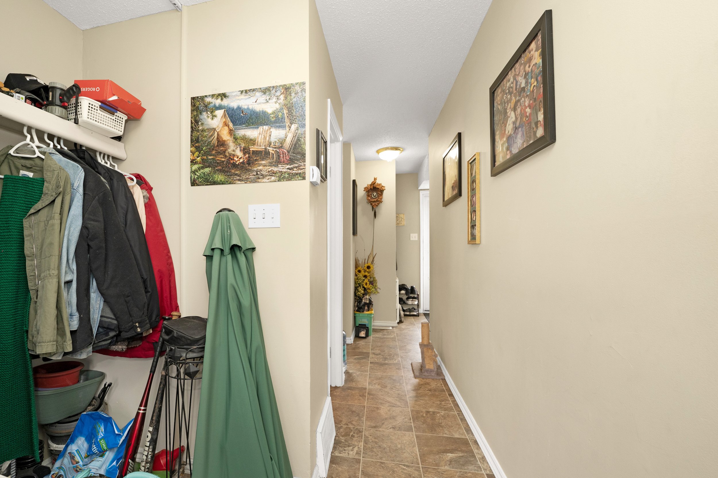 Narrow hallway with wall art and a green coat rack.