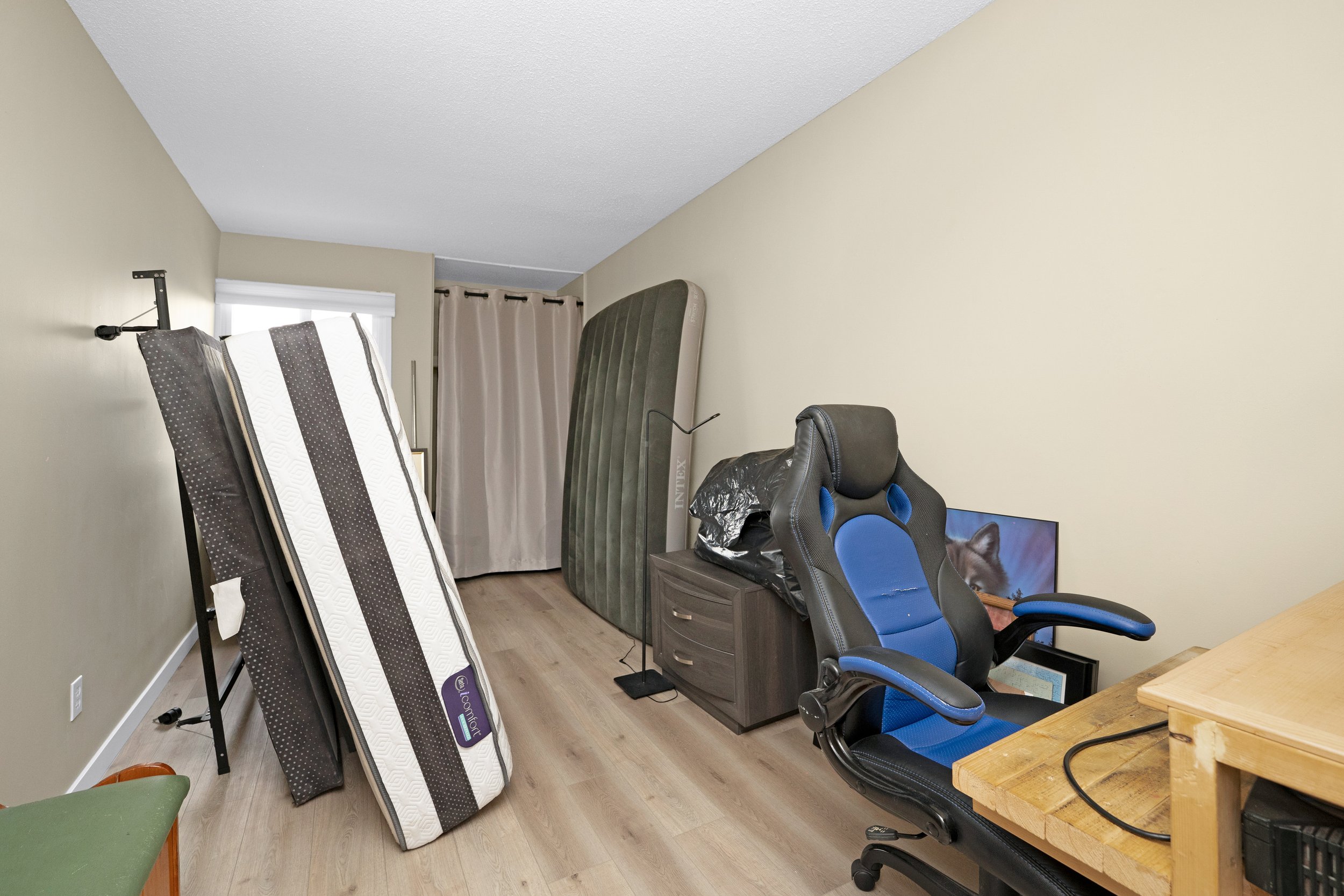 Spacious room with scattered furniture and hardwood floors.
