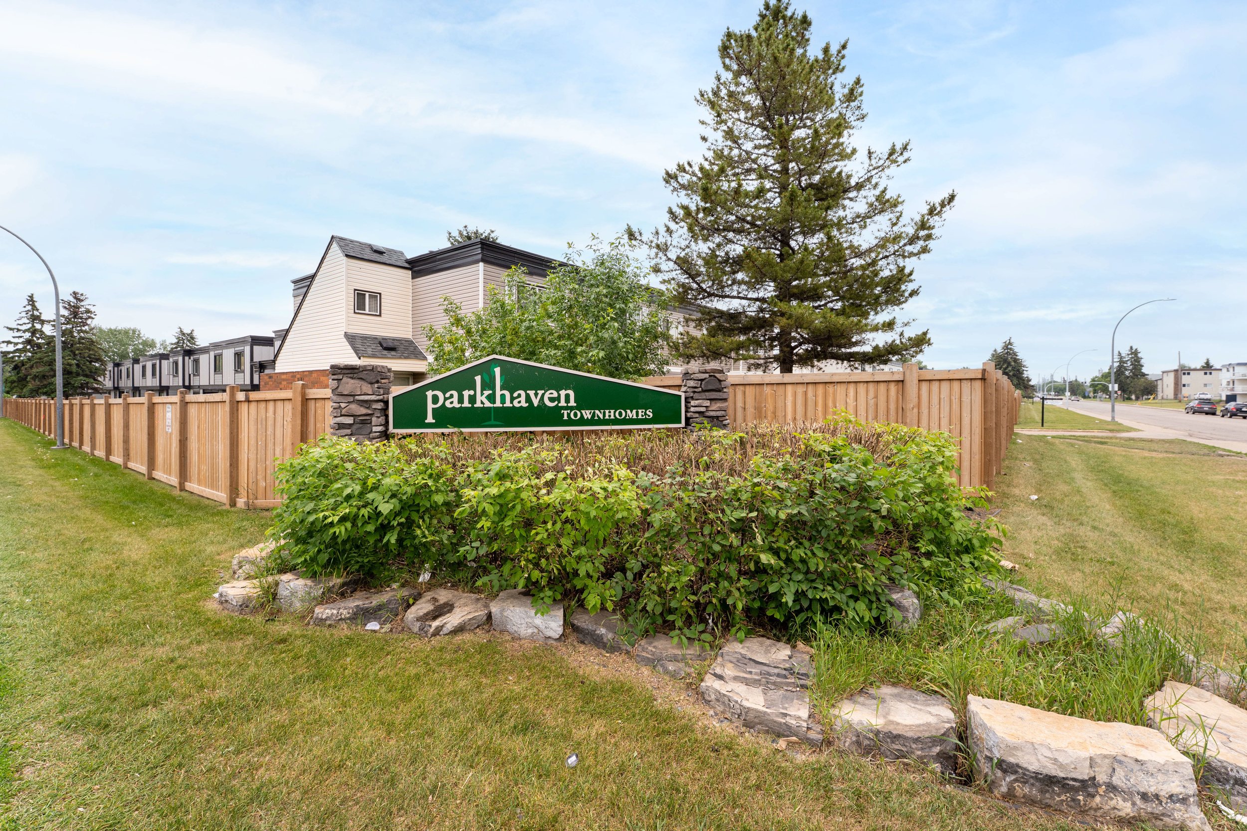 Exterior view of a rent to own apartment complex with lush green lawn and trees.